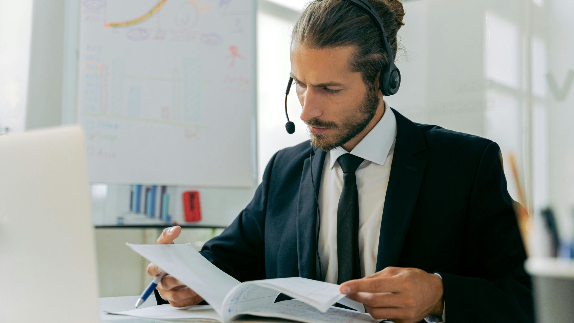 Focused business professional handling customer service tasks with a headset in an office setting.