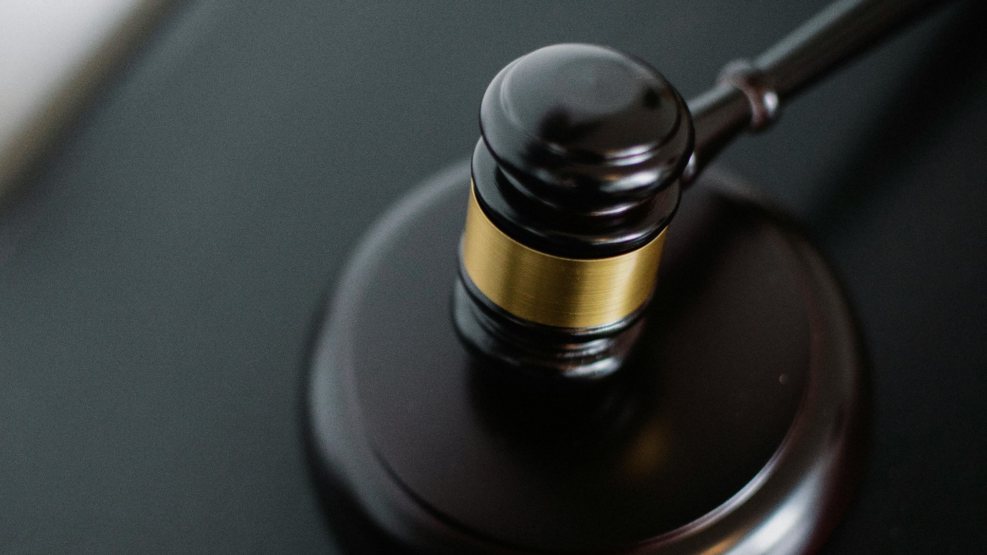 From above of wooden gavel on round surface near folders on table in courtroom