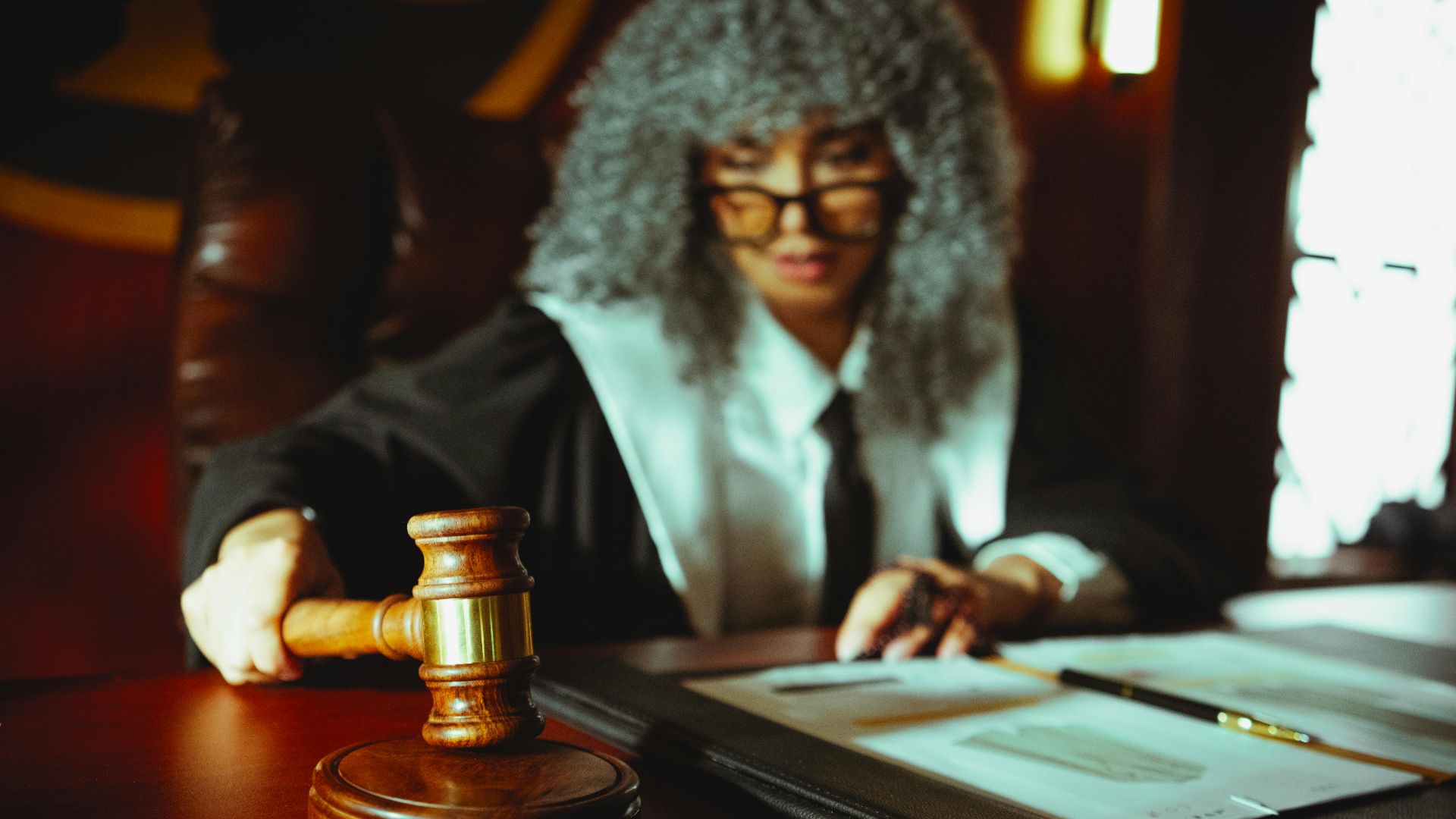 Female judge in a courtroom setting, focusing on legal documents with a gavel.