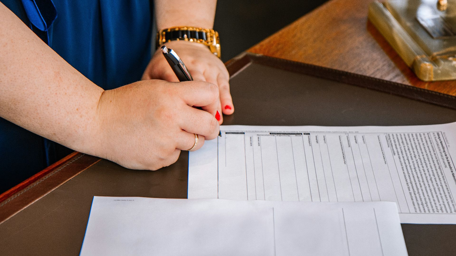 person holding pen and writing on paper