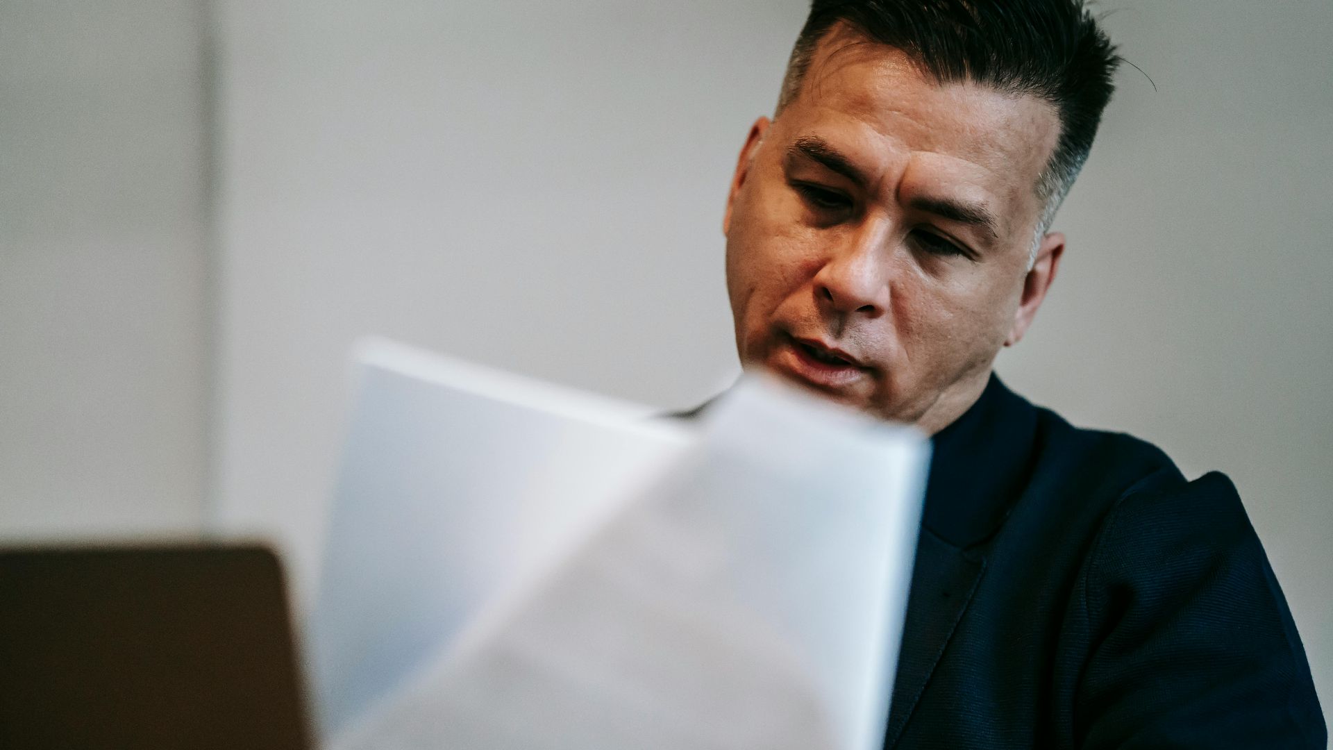 Professional man intently reviewing paperwork at his workstation indoors.