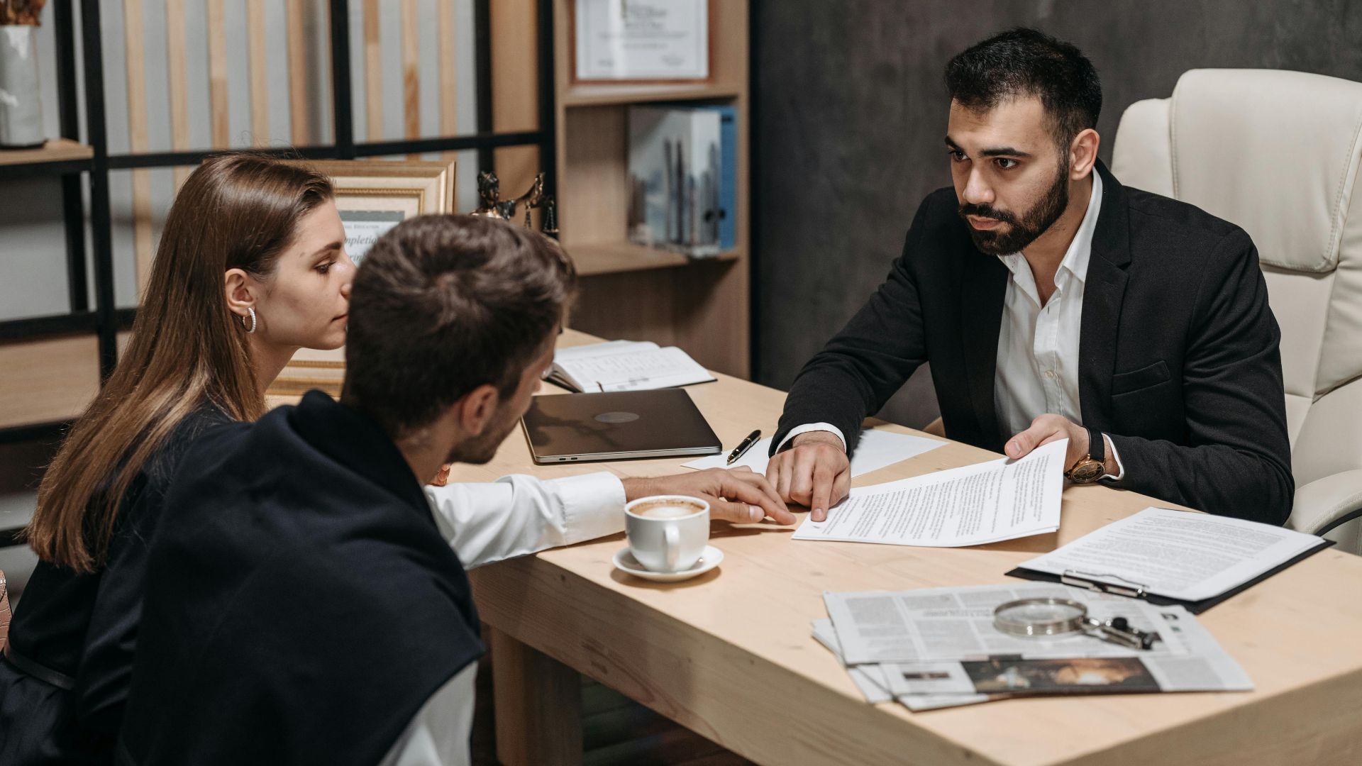 Lawyer discussing legal documents with clients at office desk.