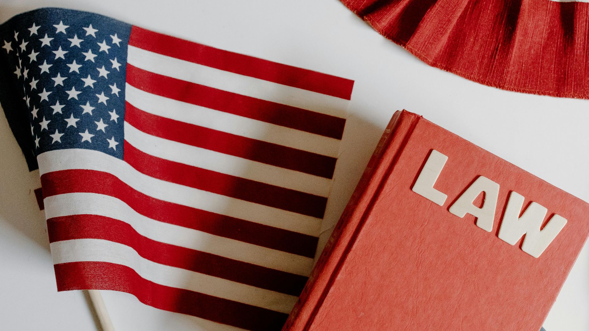 Patriotic scene with American flag and law book on a white background, symbolizing freedom and democracy.