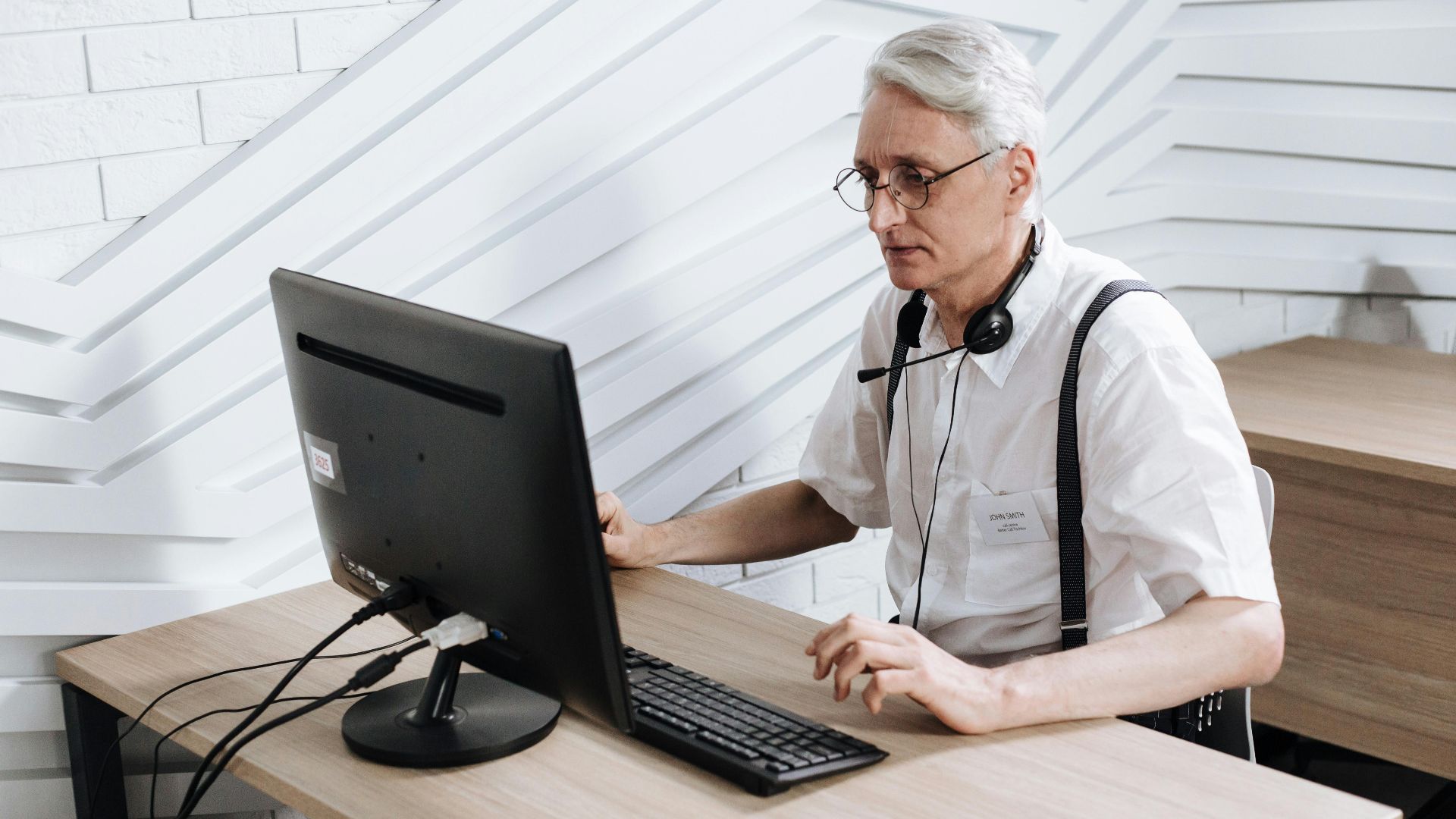 Senior adult man working in a call center with a headset and computer.