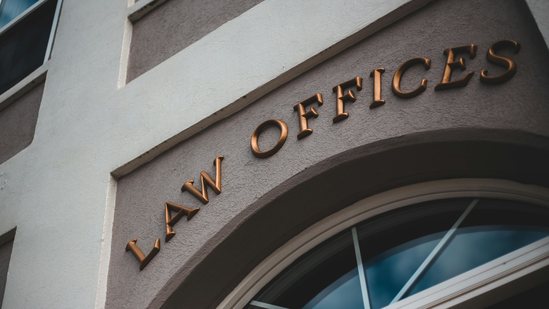 Low angle view of a modern law office exterior with elegant facade and arched entrance.