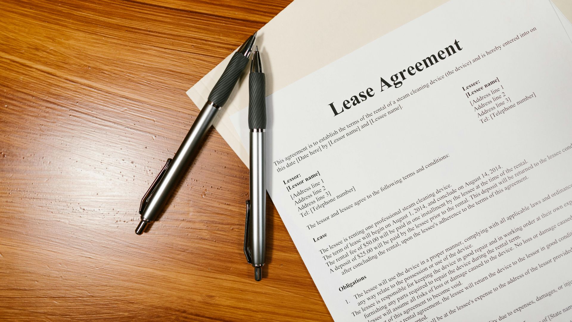 High-angle view of a lease agreement and pens on a wooden desk.