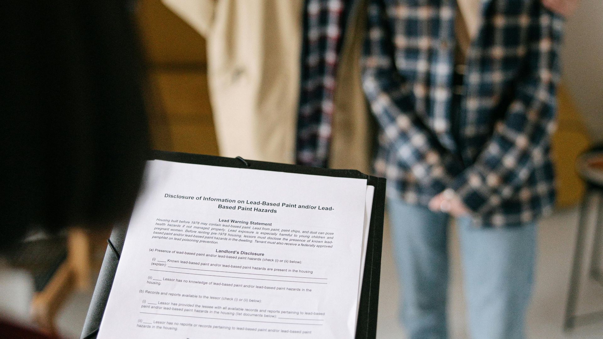A focused view of a couple discussing a real estate document with an agent in an apartment setting.