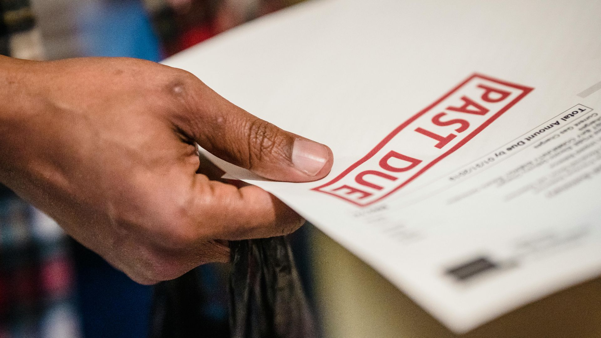 A close-up of a hand holding a document with a 'Past Due' stamp, highlighting financial urgency.