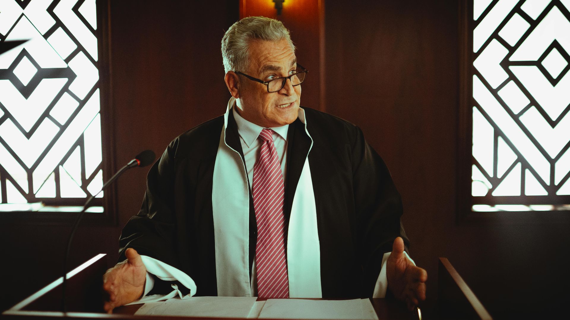 Senior male lawyer presenting a case in a Baghdad courtroom, wearing a classic black robe.