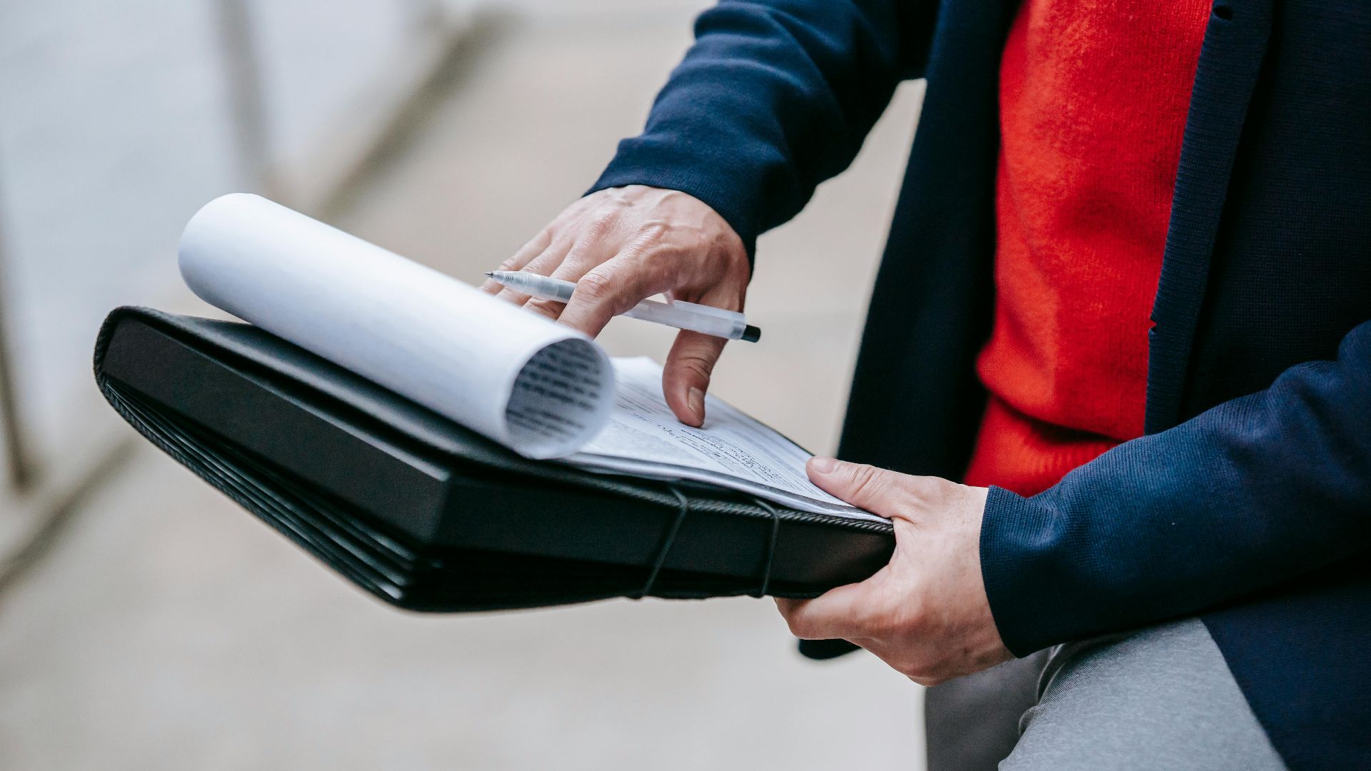 Close-up of a professional person reviewing documents outdoors. Engaged in work with focus on writing materials.