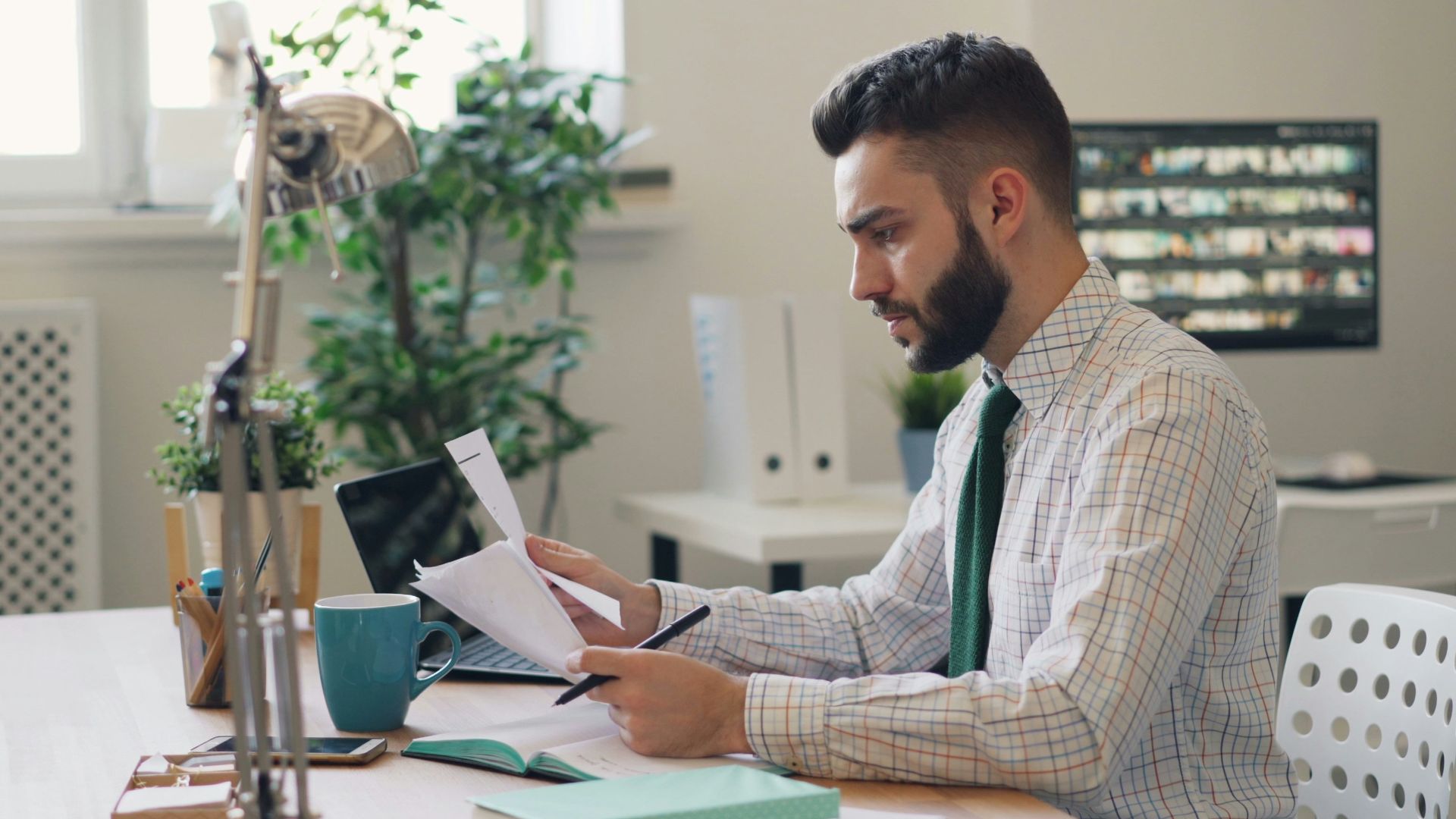 a man sitting at a desk with a laptop and papers