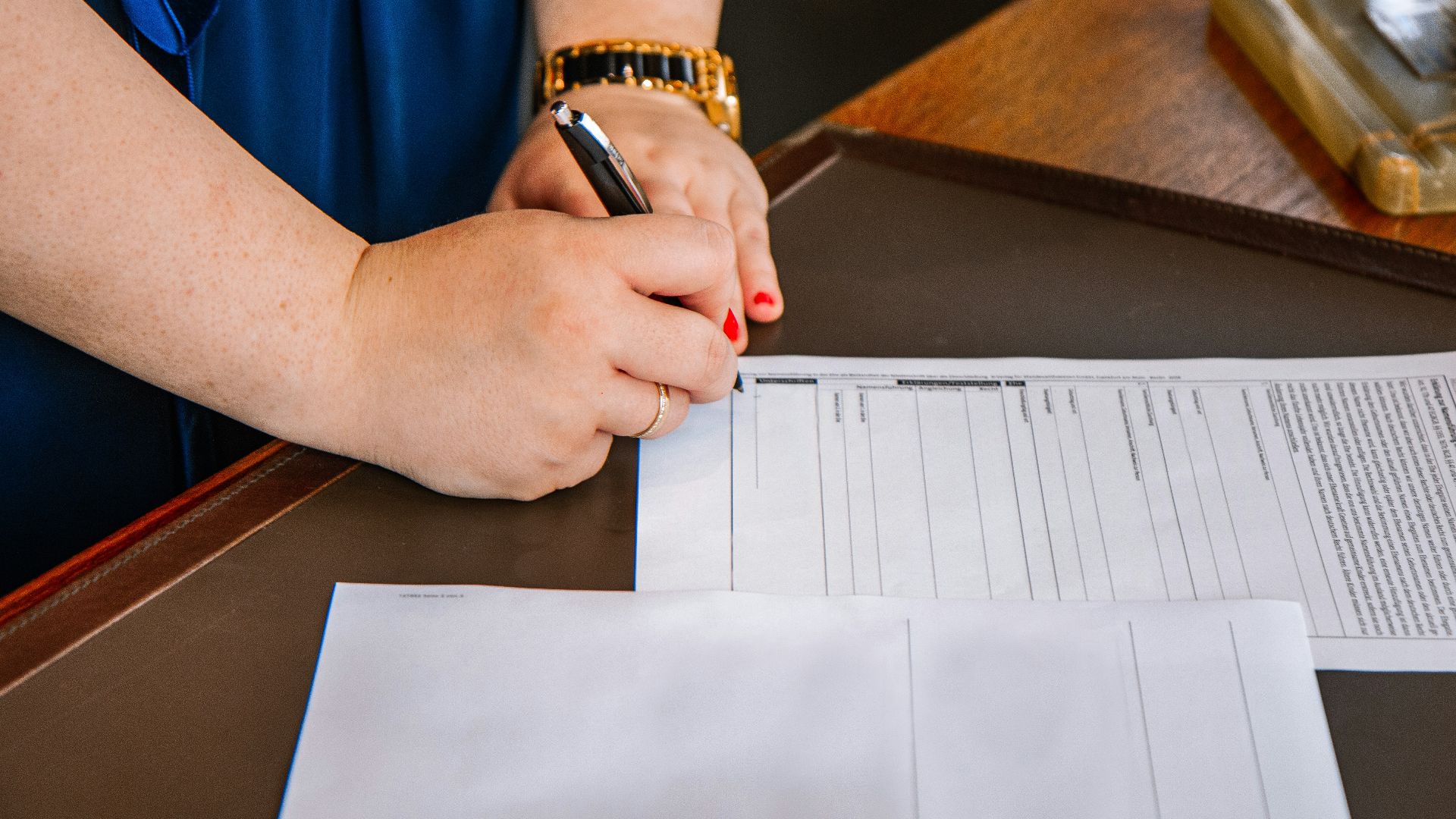 person holding pen and writing on paper