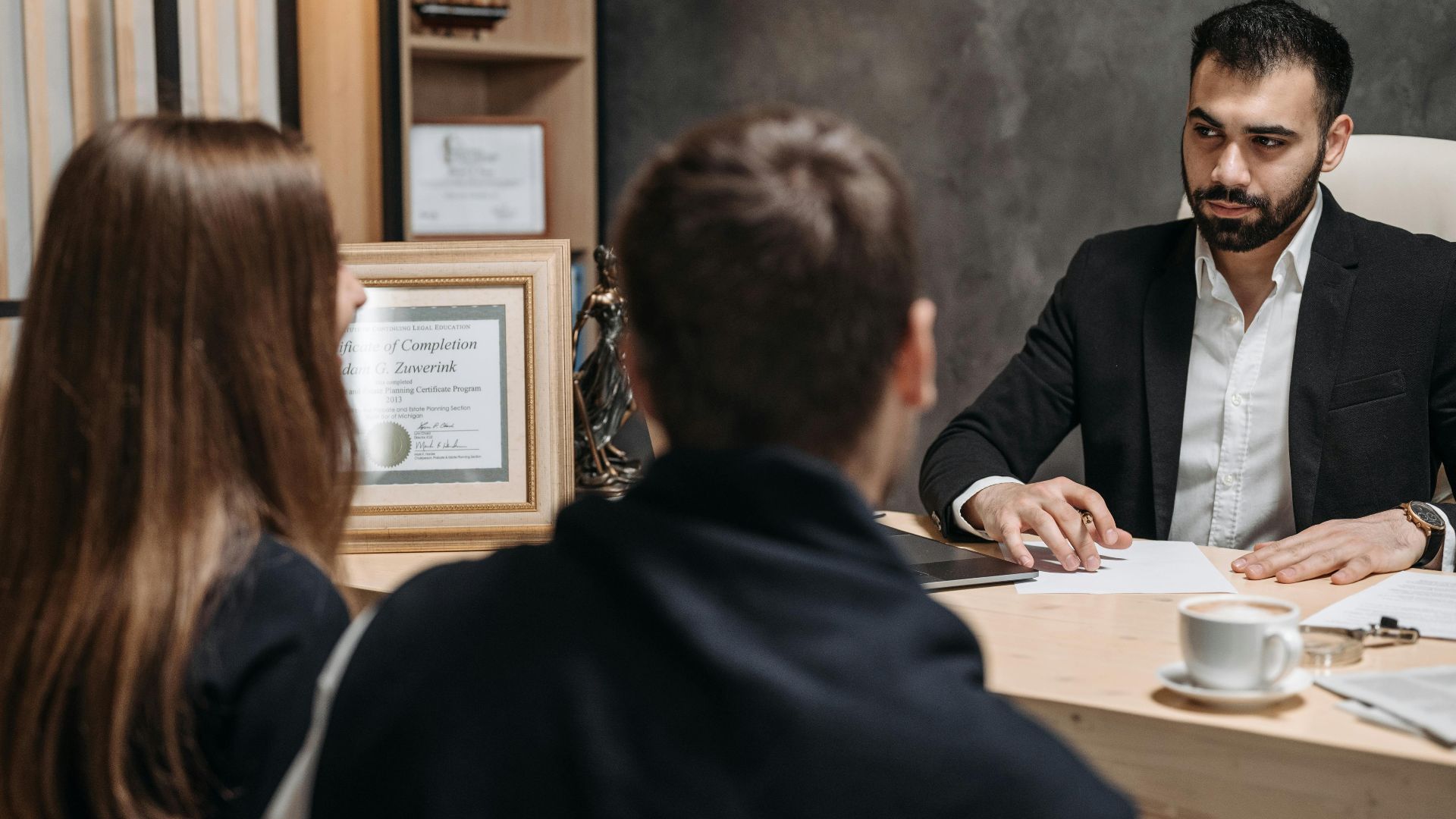 A lawyer in an elegant office meeting with clients, discussing documents.