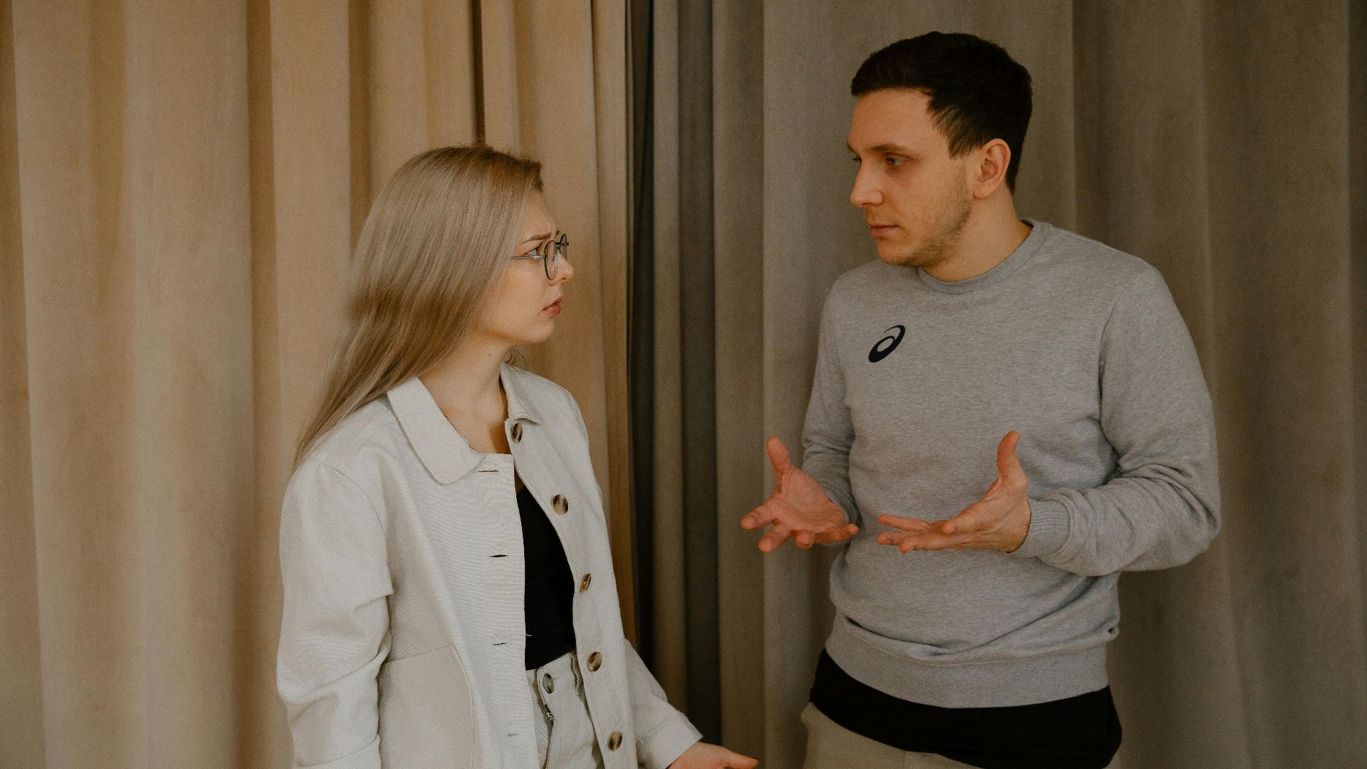 A young couple passionately discussing indoors, capturing intense emotions and gestures.