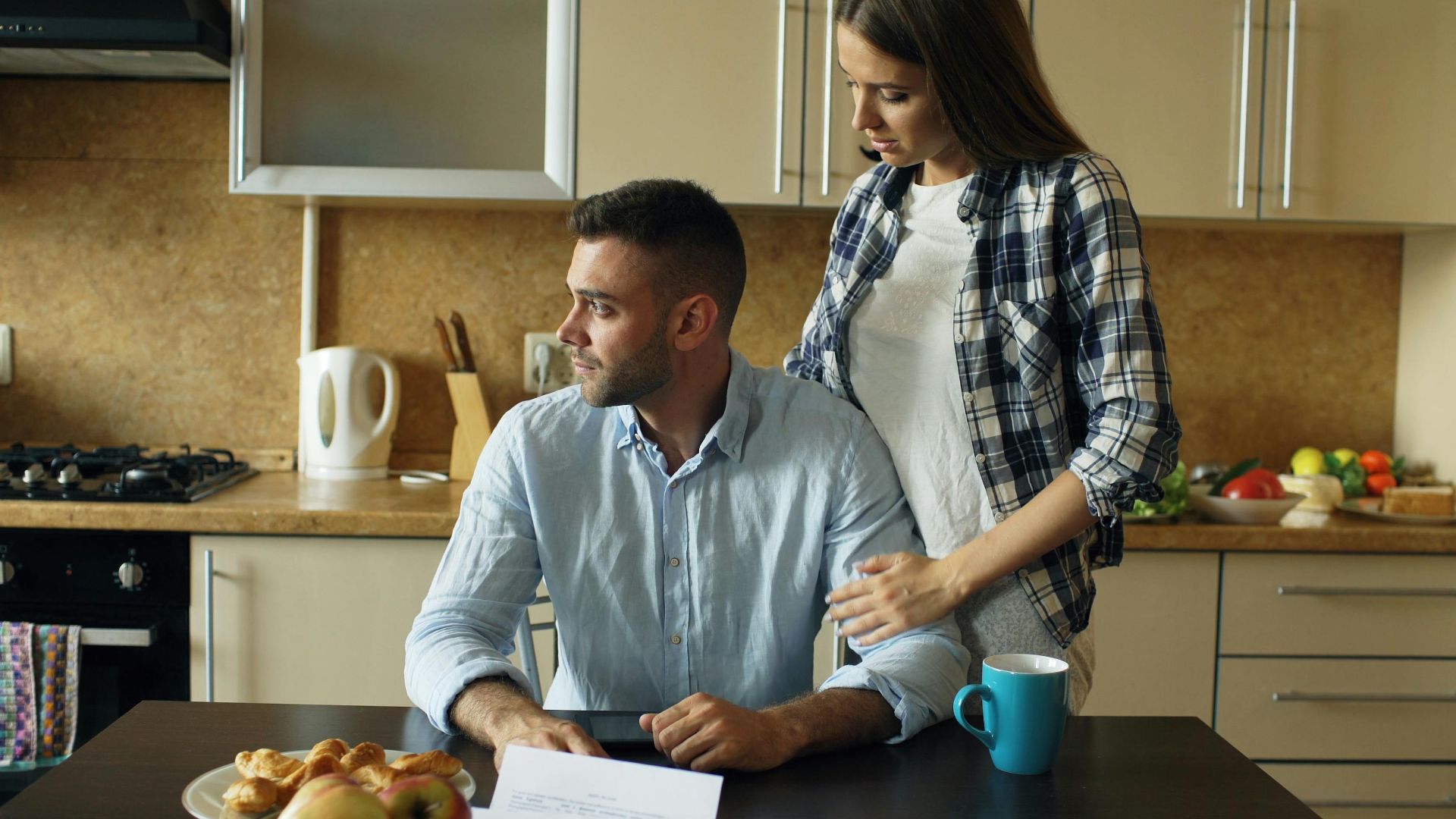 A couple having a serious discussion over breakfast papers in a modern kitchen.