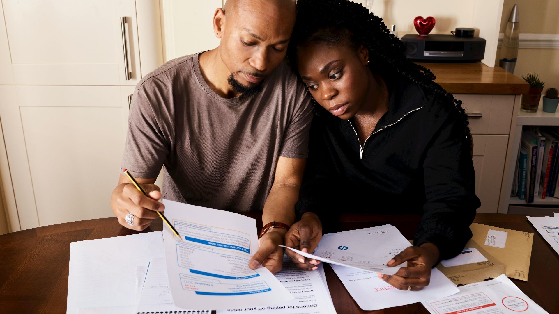 A couple sitting at a table reviewing financial documents, highlighting domestic budgeting.