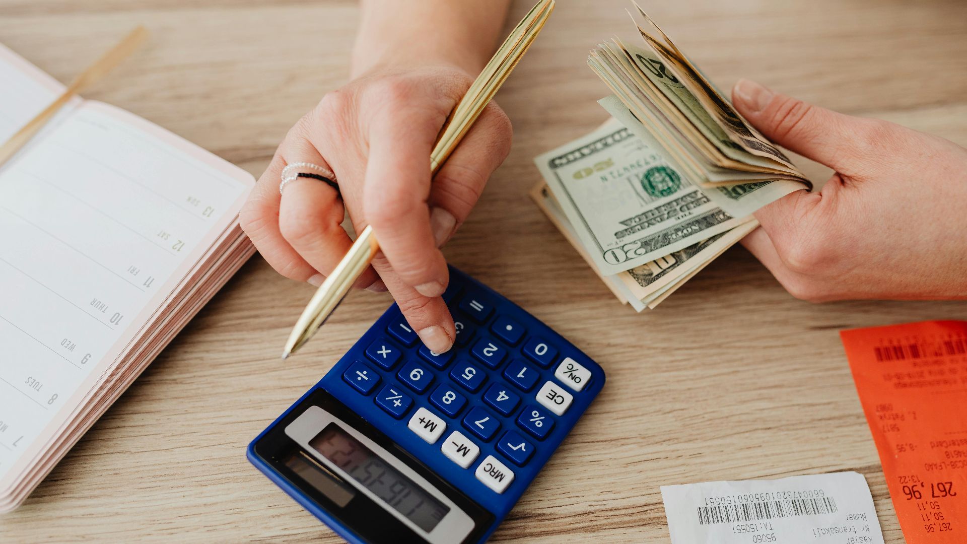 Hands handling cash and calculator for budget planning. Modern financial scene.