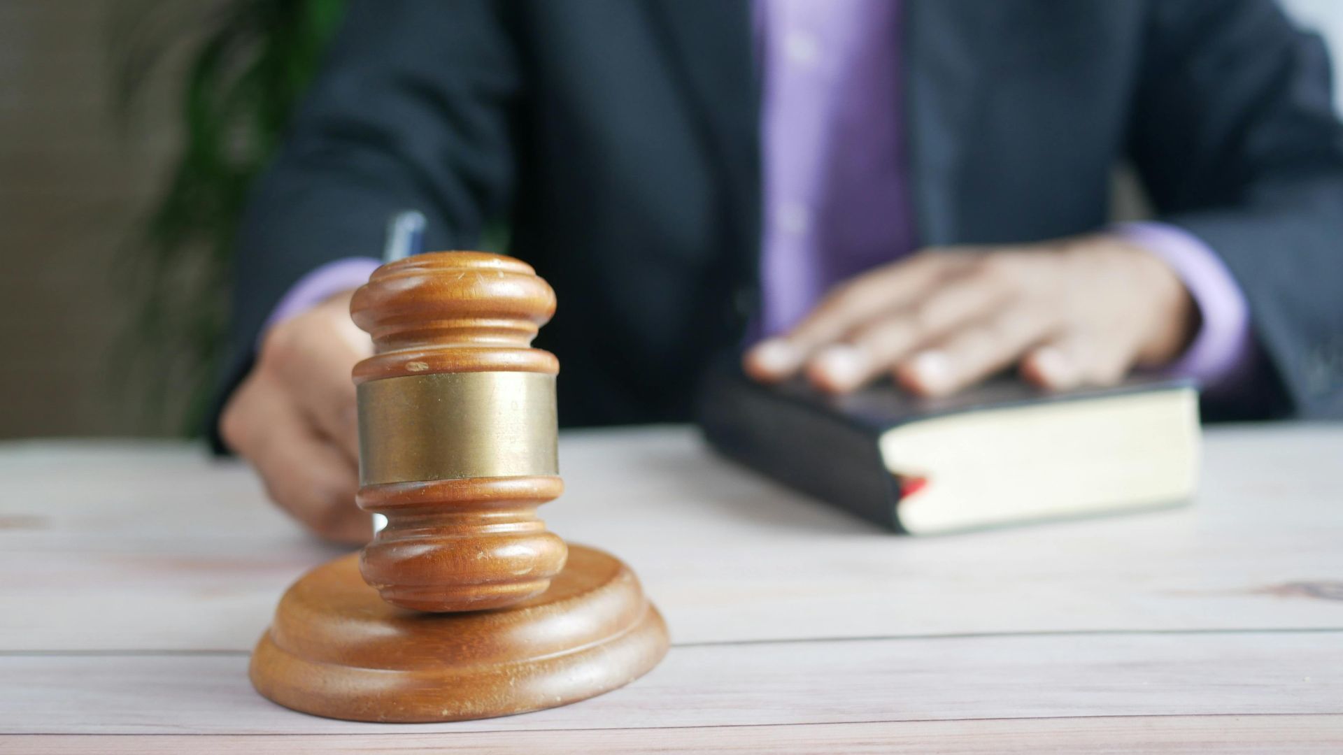A wooden gavel and legal book represent justice in a court setting, emphasizing order and legal authority.