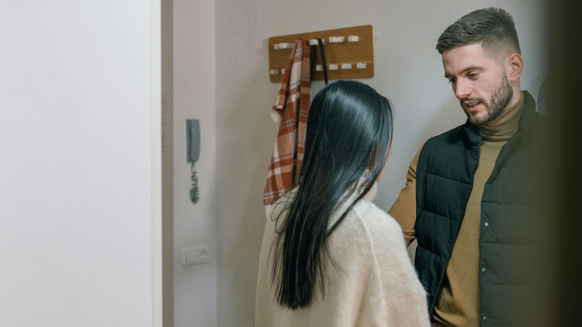 A man and woman talk inside a cozy home. They appear engaged in a conversation.