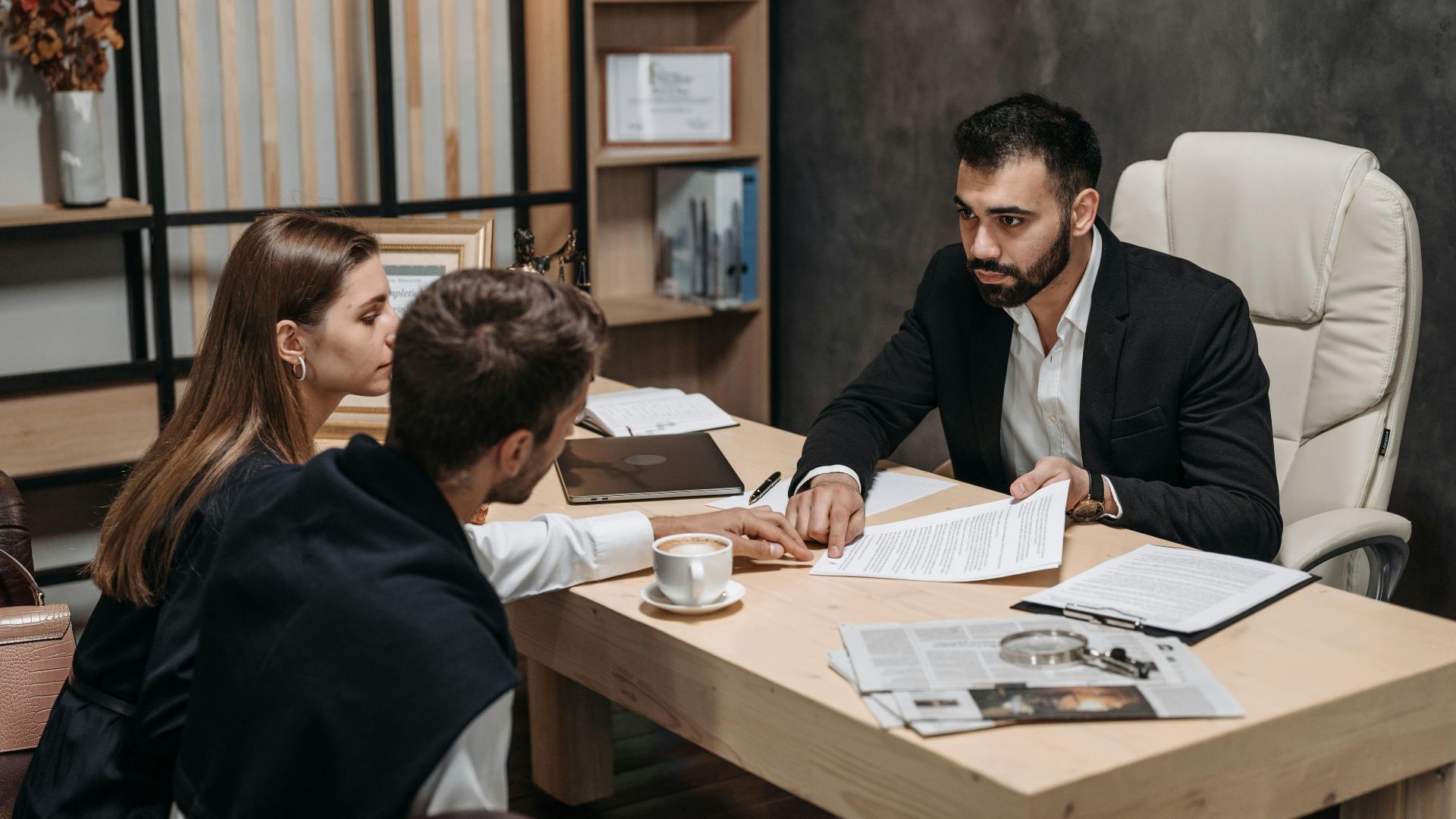 Lawyer discussing legal documents with clients at office desk.