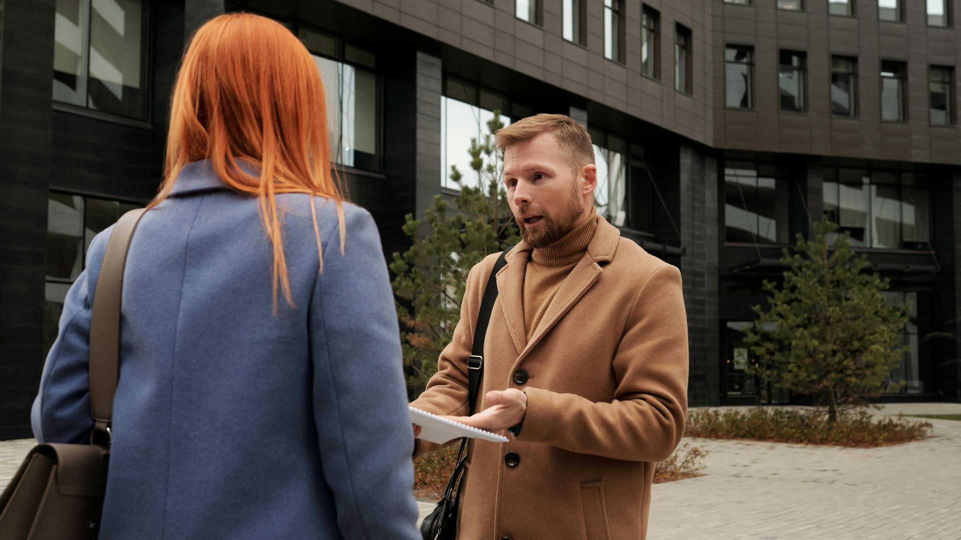 Two business professionals in conversation outside an urban office building.