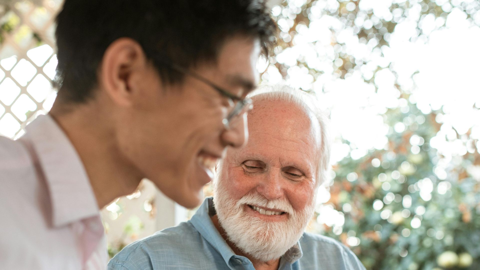 A senior man and an adult in a friendly conversation outdoors, enjoying a casual moment.