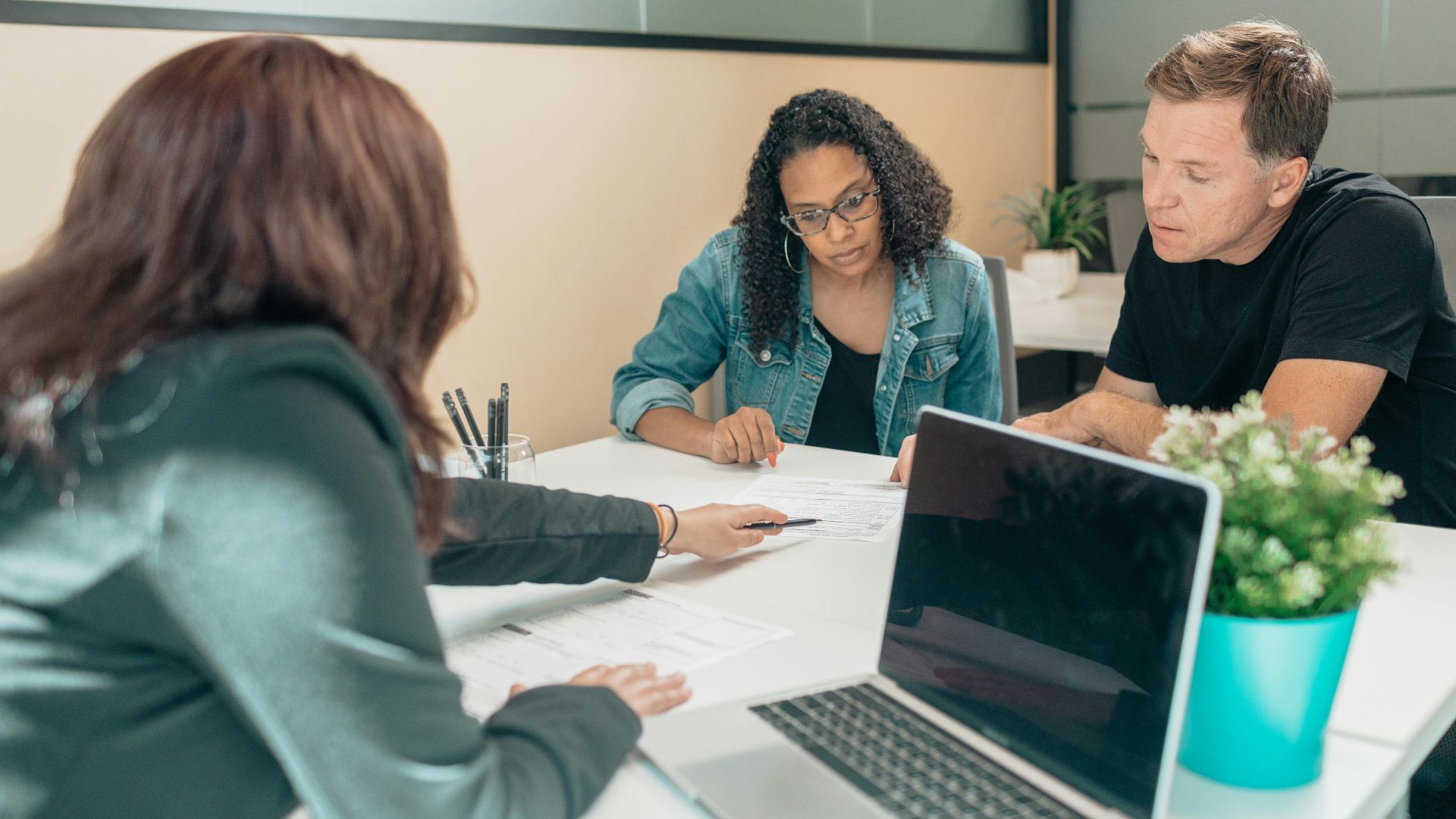 Couple meeting with advisor for adoption process in a modern office setting.