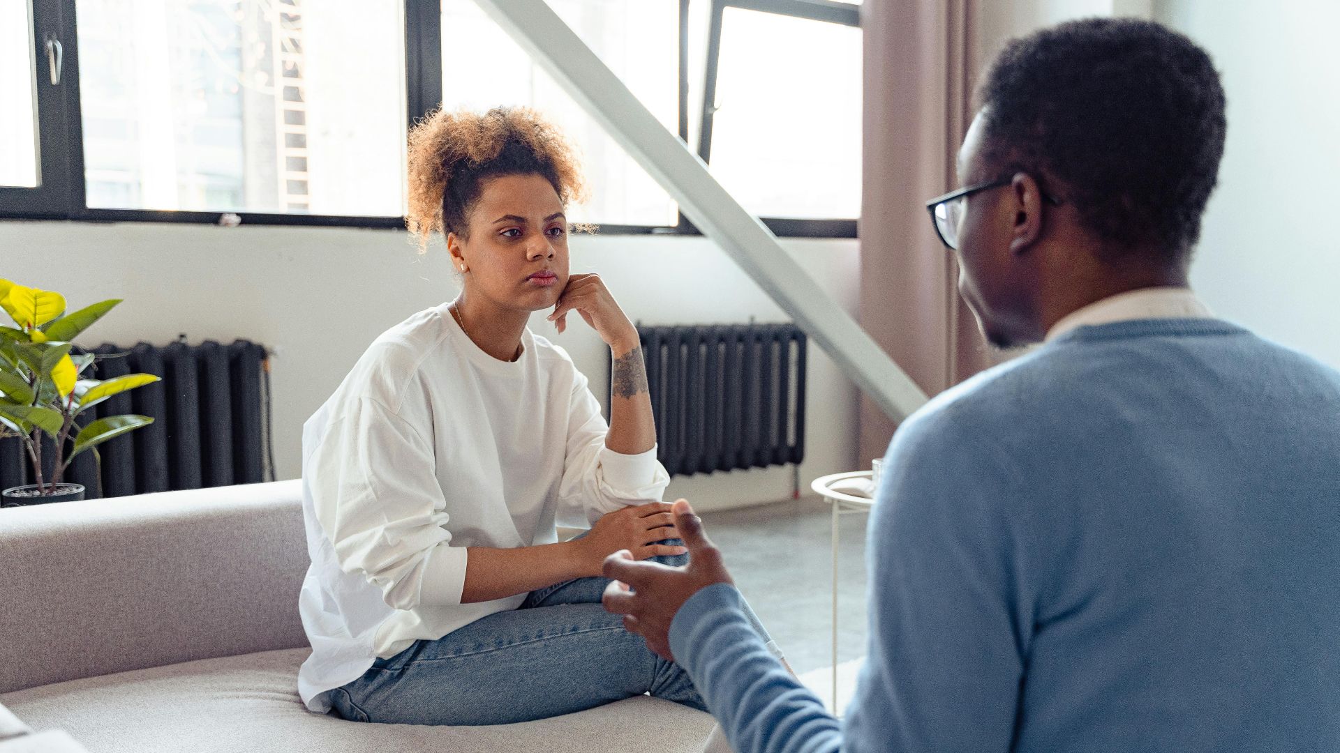 Two individuals engaged in a thoughtful therapy session indoors.