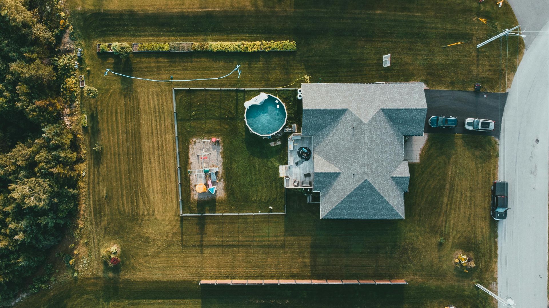 Drone shot of a house and garden with a swimming pool and play area.