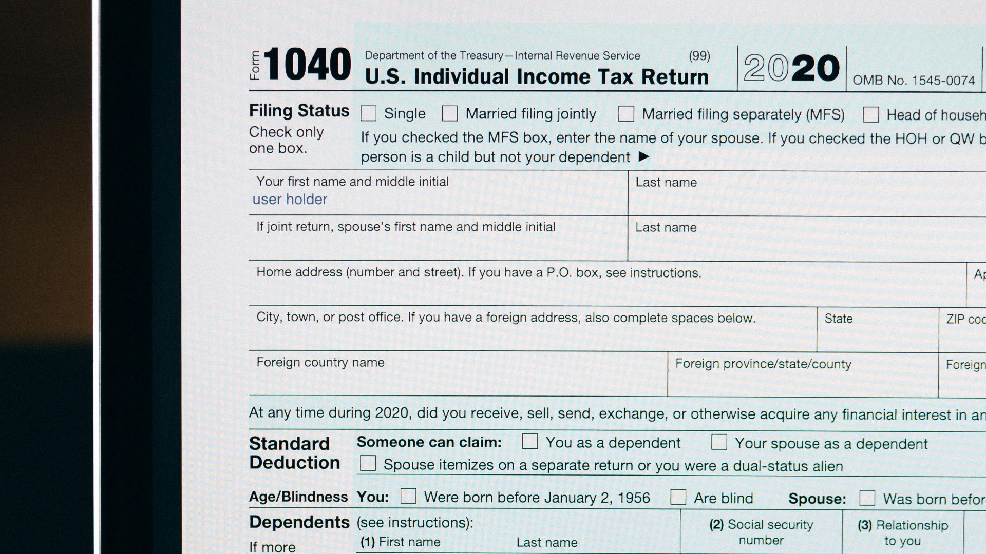 Close-up of a tax form on a laptop screen with a calculator and notebook in the foreground.