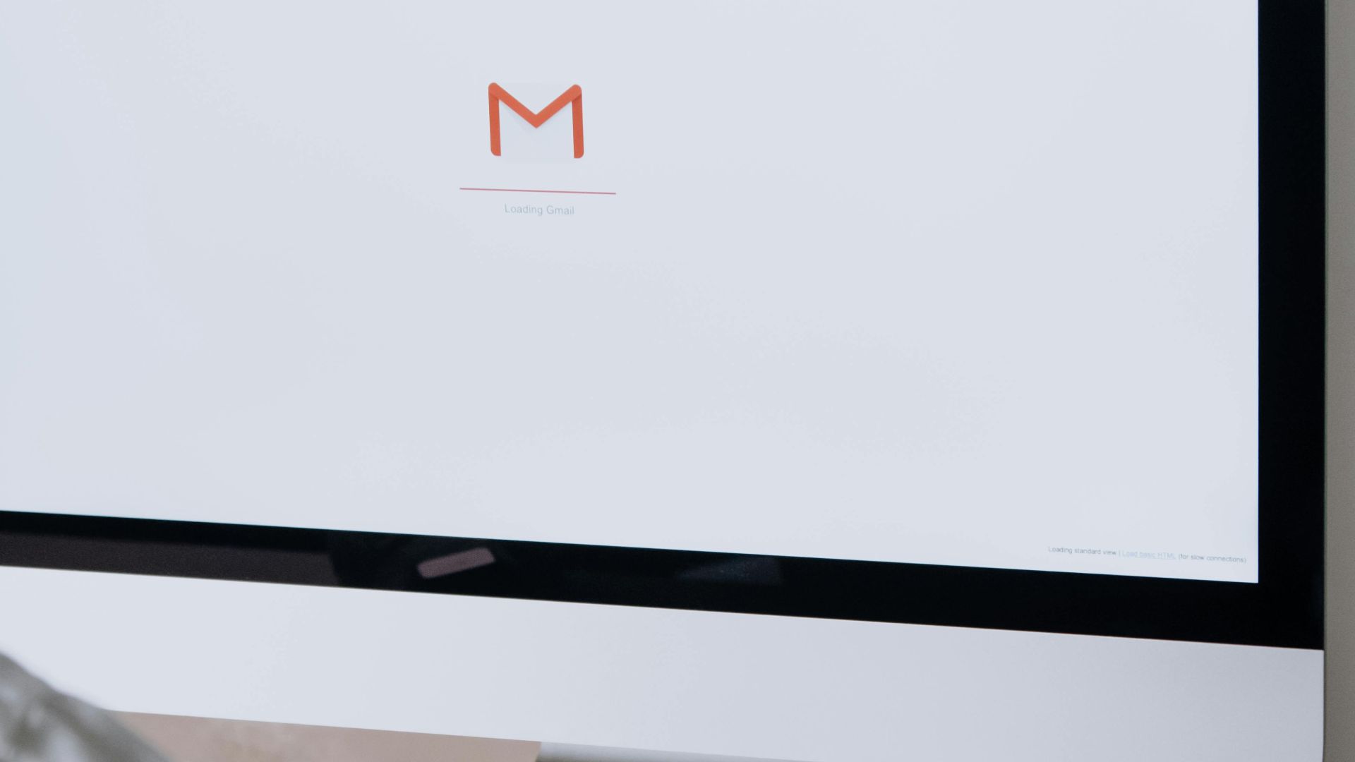 A professional in an office setting checking emails on a desktop computer with a clean workspace.