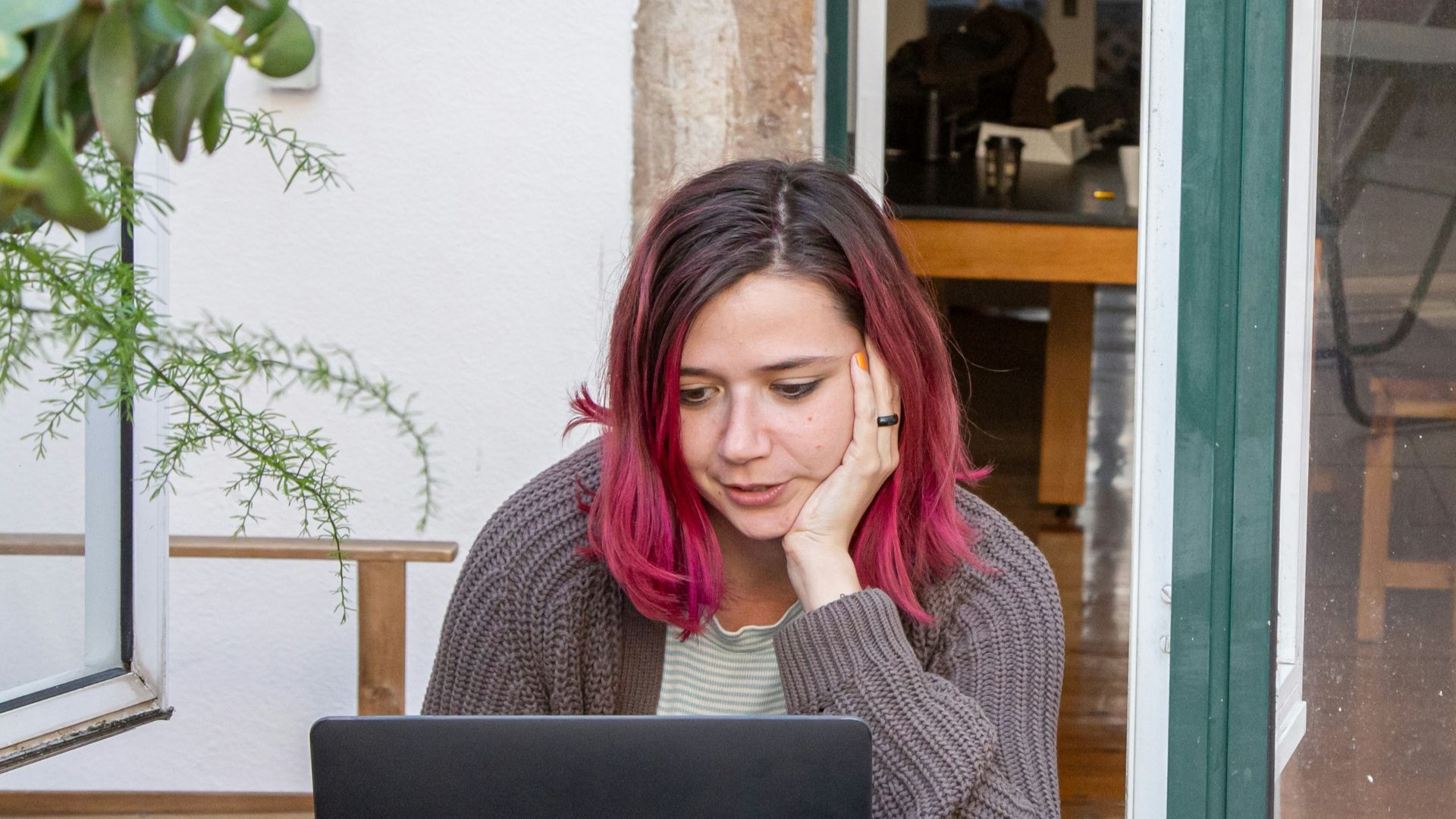 a woman with pink hair is looking at a laptop