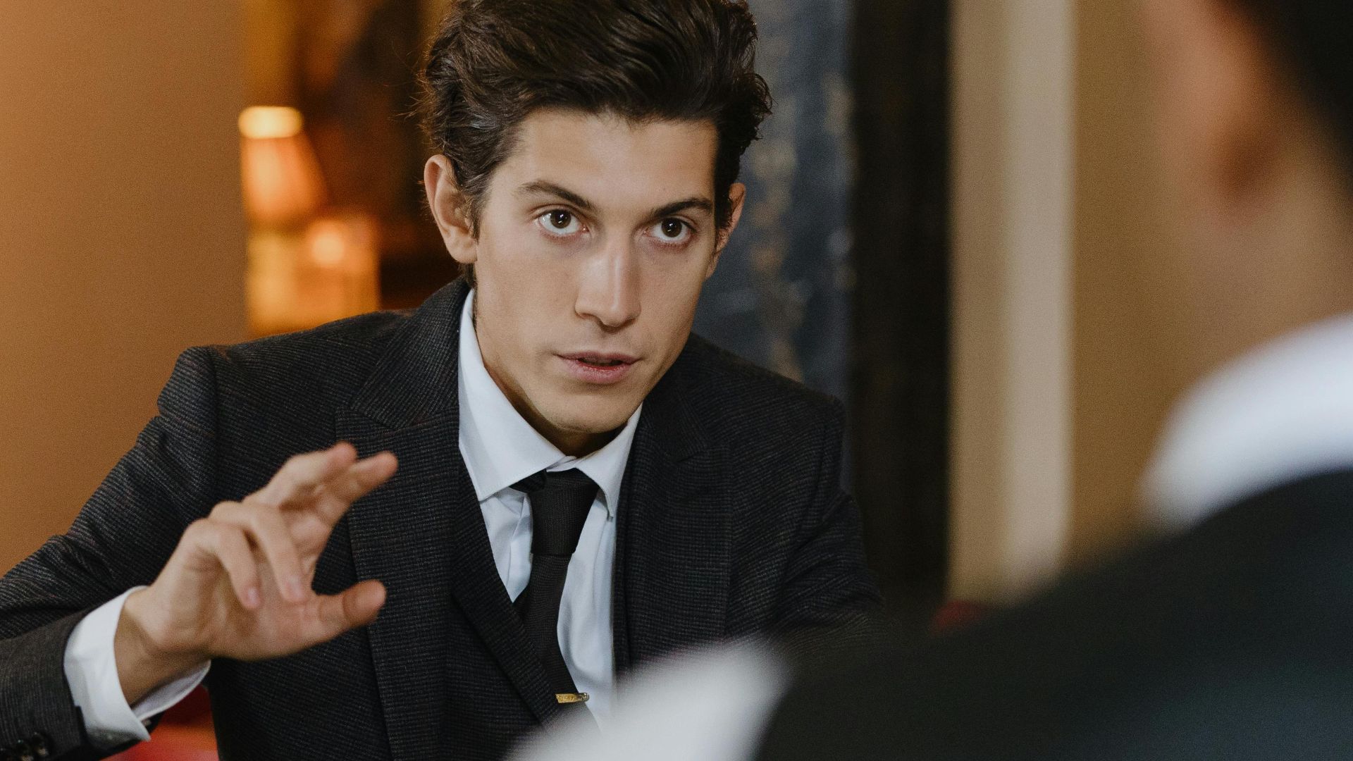 A classy interaction between a gentleman and a waiter at a stylish vintage bar setting.