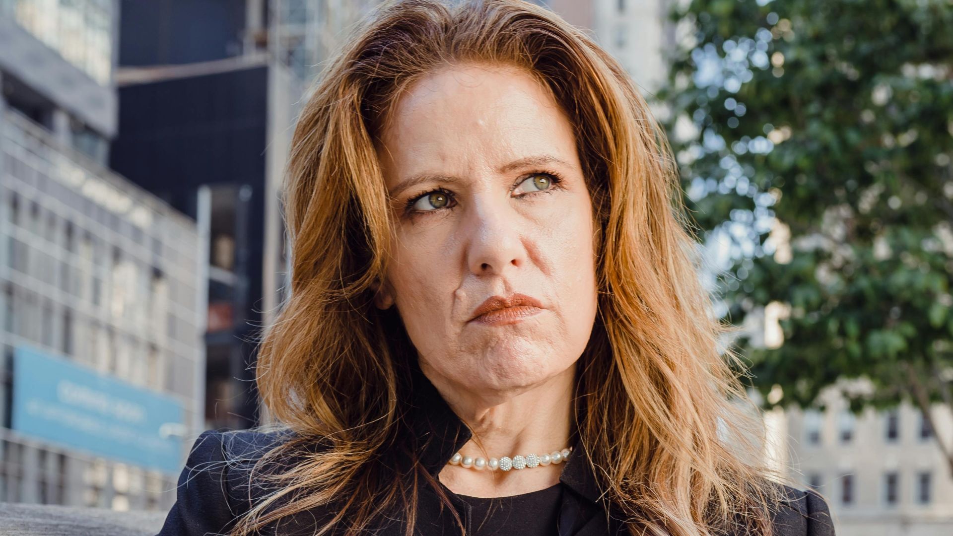 Thoughtful businesswoman using tablet outside modern office building.
