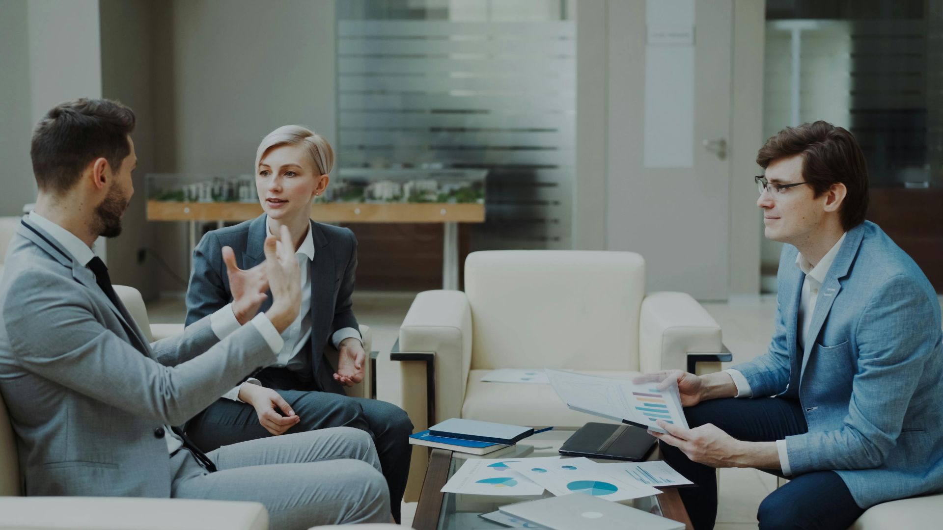 Three professionals engaged in a meeting with documents and charts in a modern office.