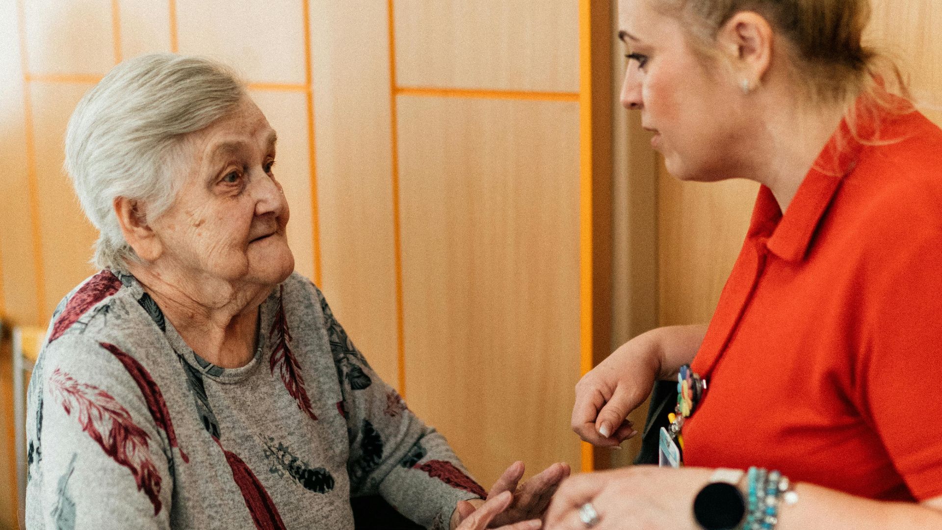 A caregiver assists an elderly woman in a retirement home corridor, fostering companionship and support.