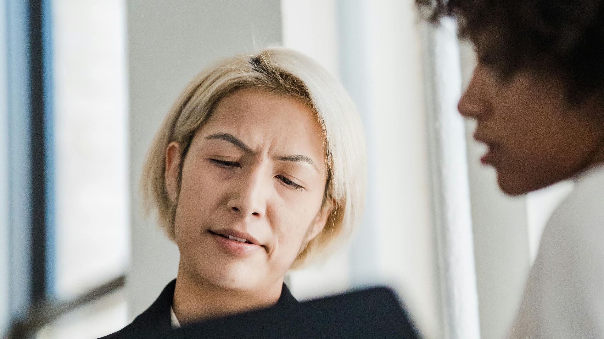 Two colleagues engaged in a business discussion while reviewing documents in an office setting.