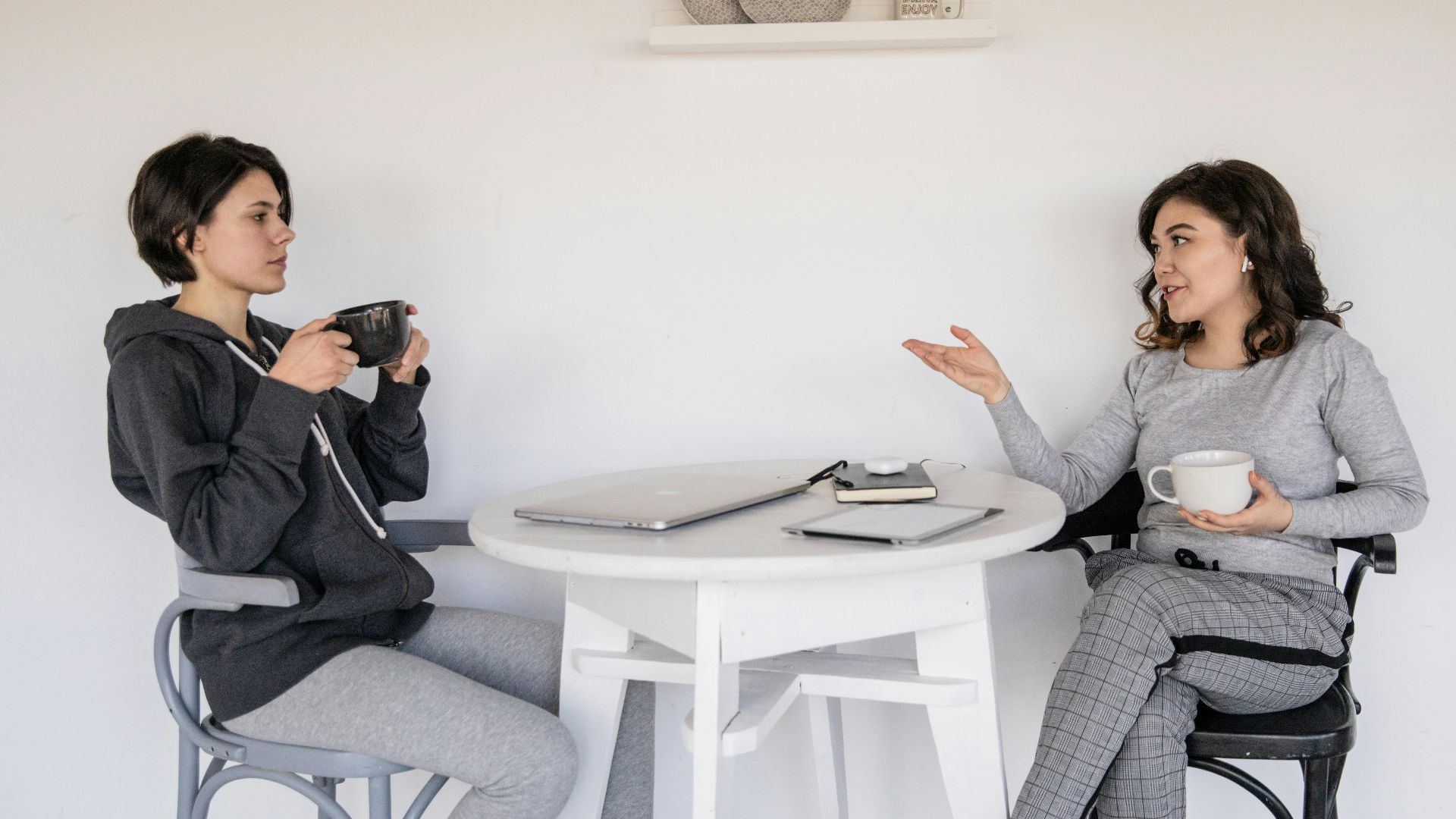 Two women enjoying a casual conversation with coffee in a cozy indoor setting, enhancing connections.