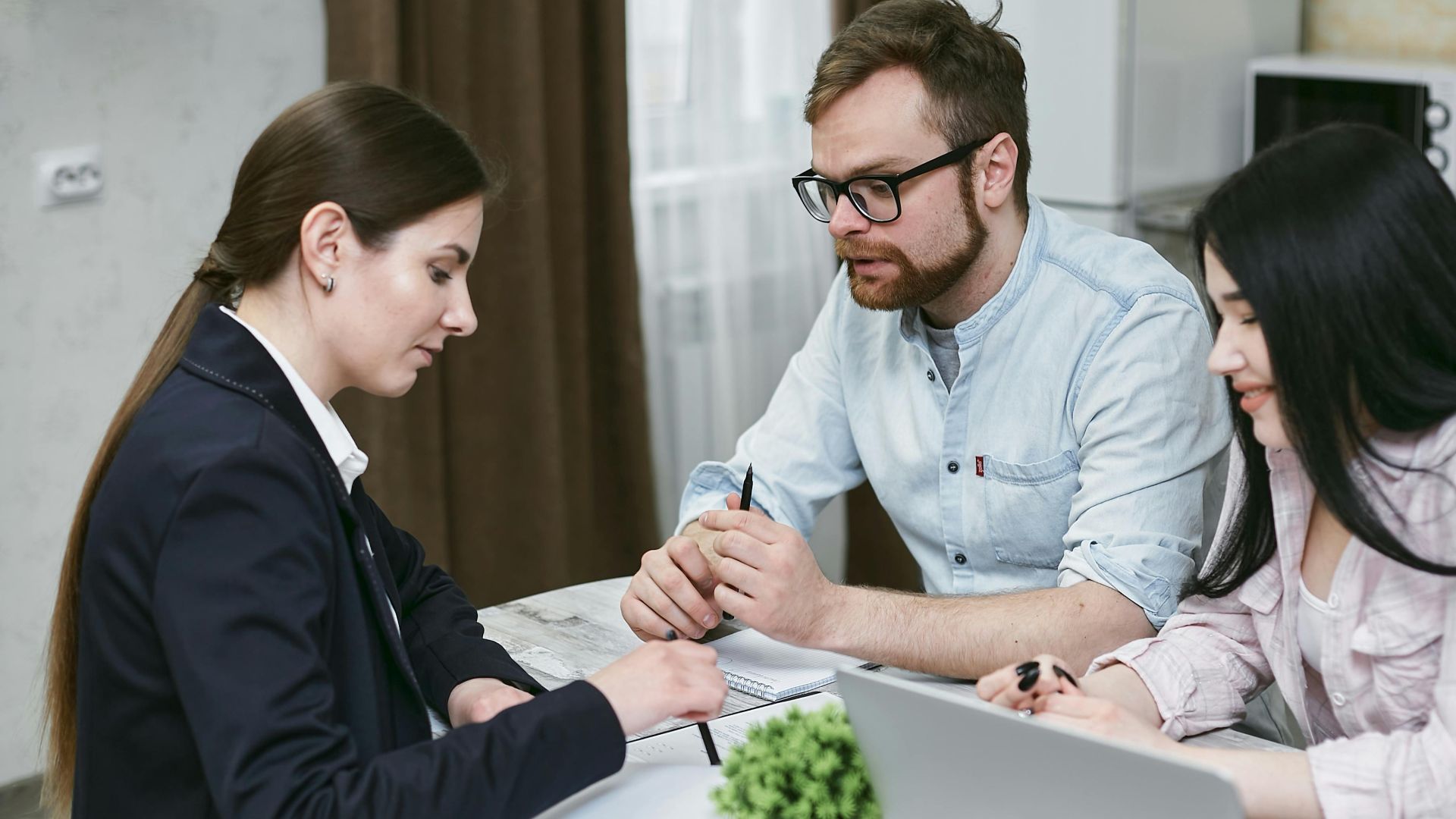 A couple discusses financial documents with their advisor, highlighting investment strategies.