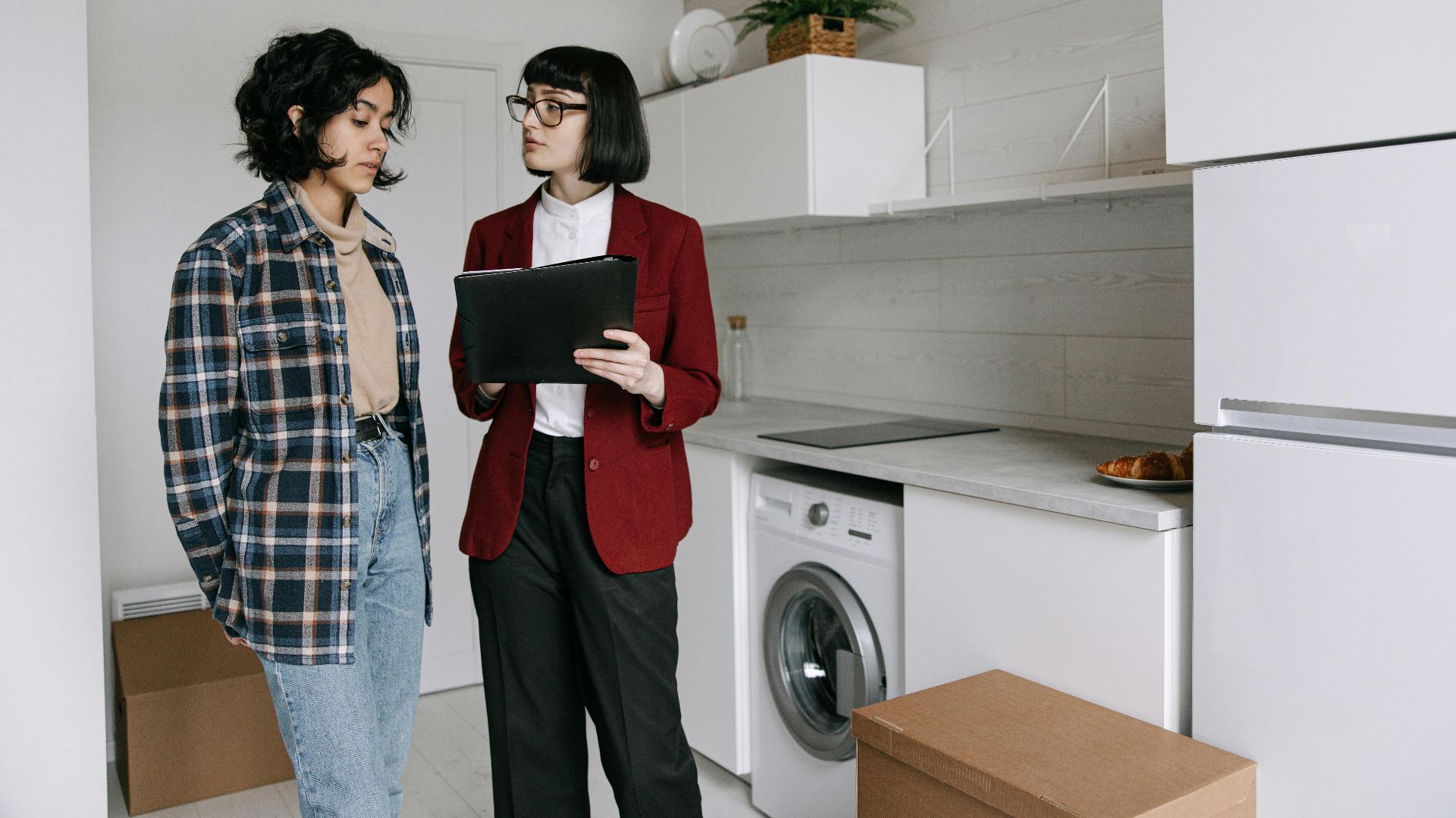 Real estate agent discussing home details with a client in a modern kitchen setting.