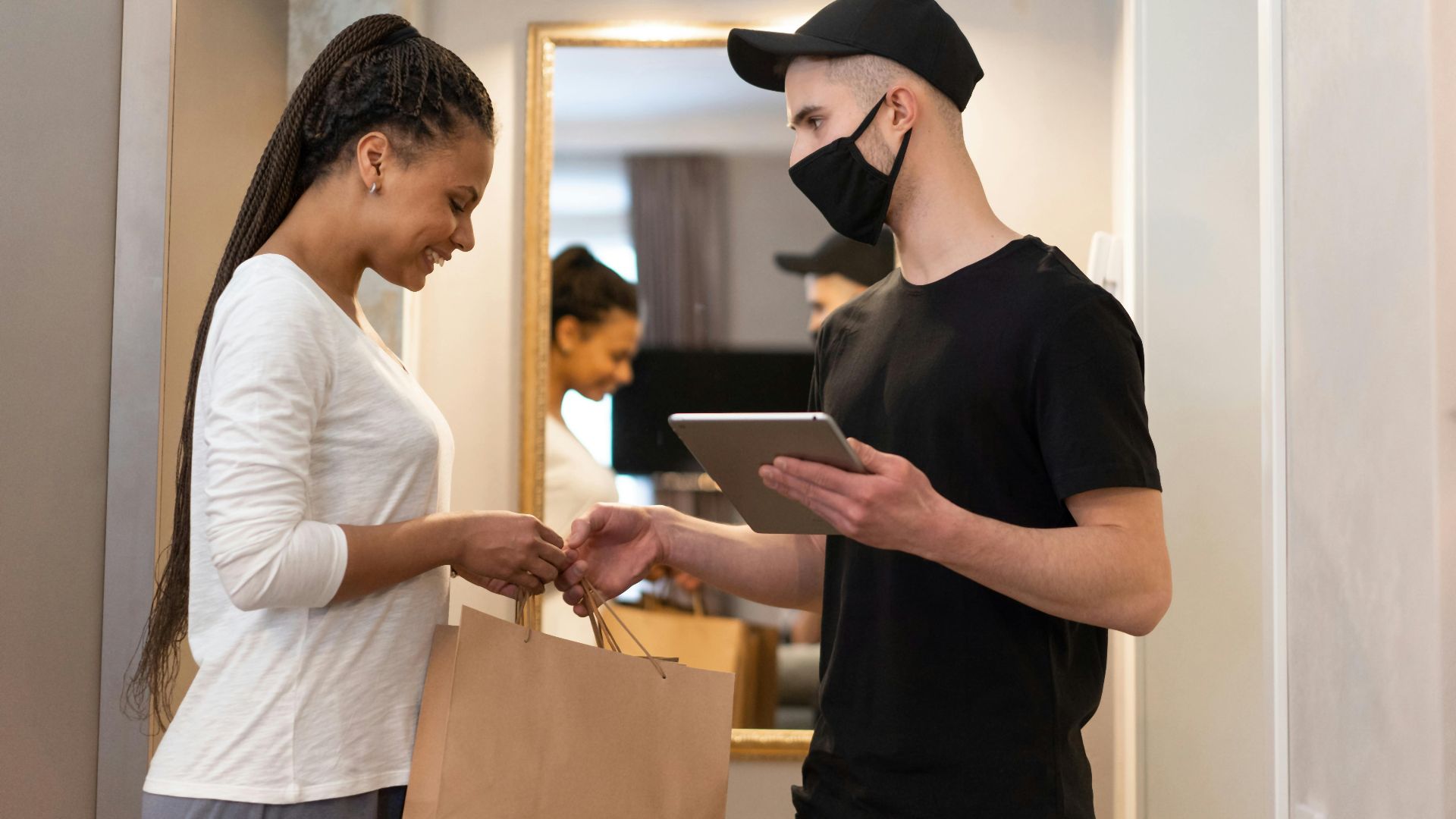 A delivery person hands over a package to a smiling woman in an apartment, emphasizing safety and convenience.