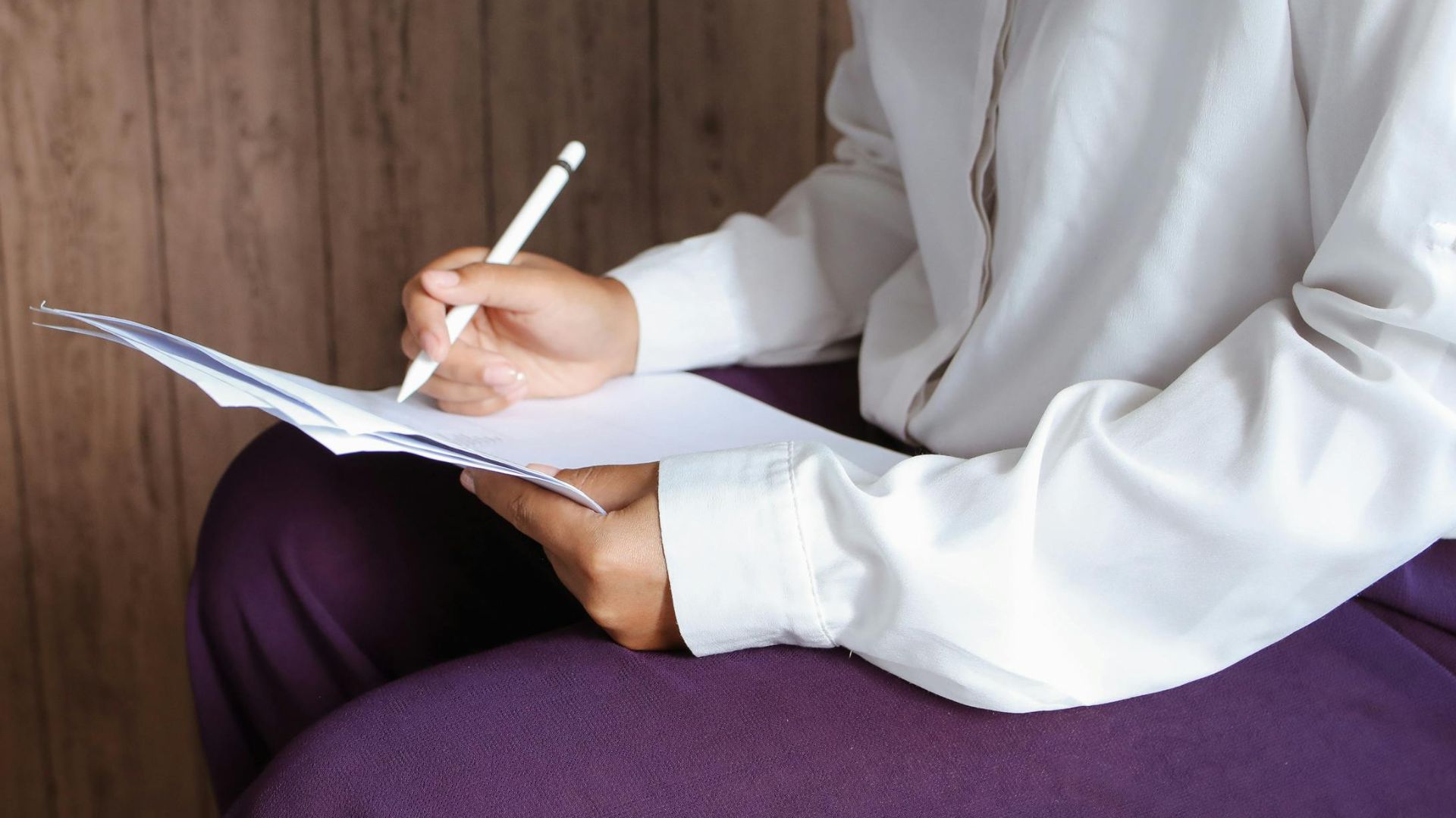 Two women collaborating indoors, focused on documents in a casual setting.
