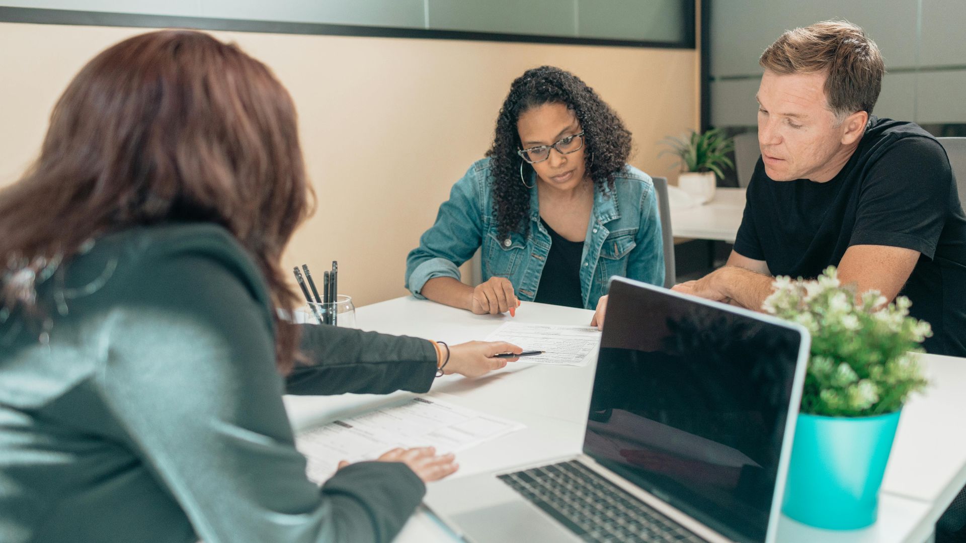 Couple meeting with advisor for adoption process in a modern office setting.