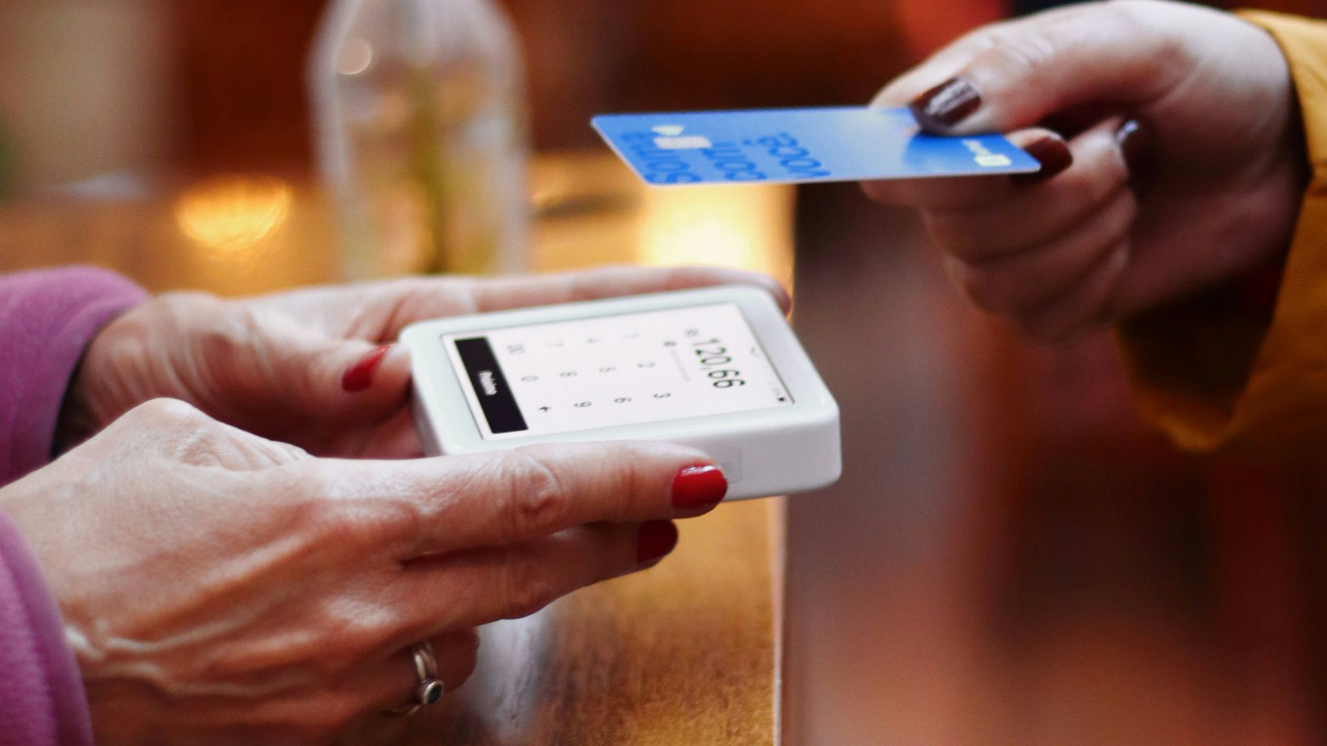 two people exchanging a credit card at a table
