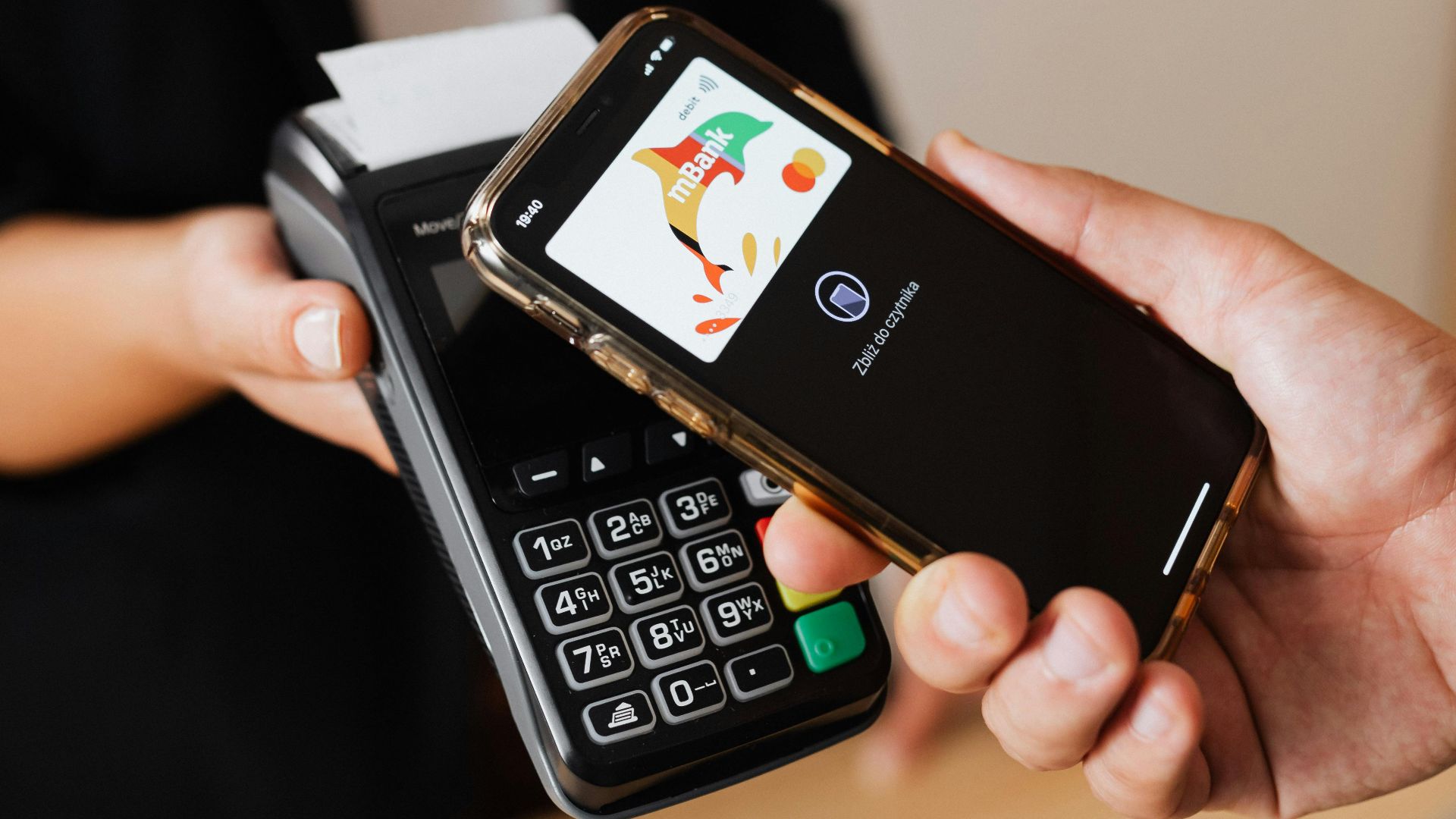 A person pays using a smartphone with contactless technology at a retail payment terminal.