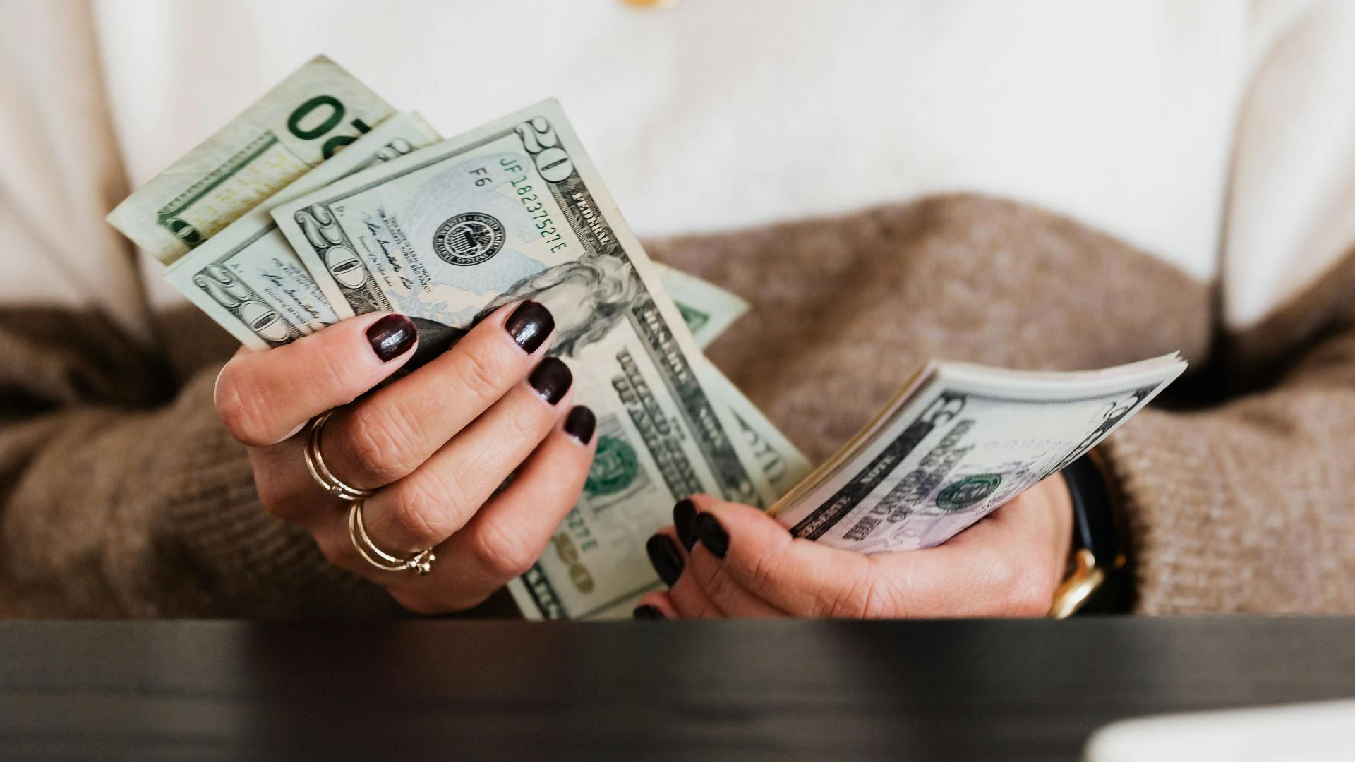 Close-up of hands counting US dollar bills, depicting finance and money handling.