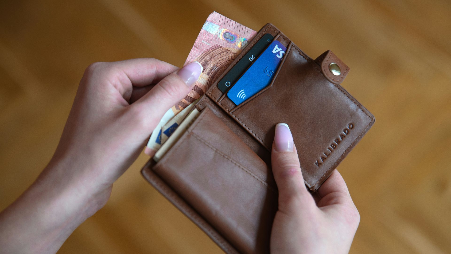 person holding brown leather card wallet