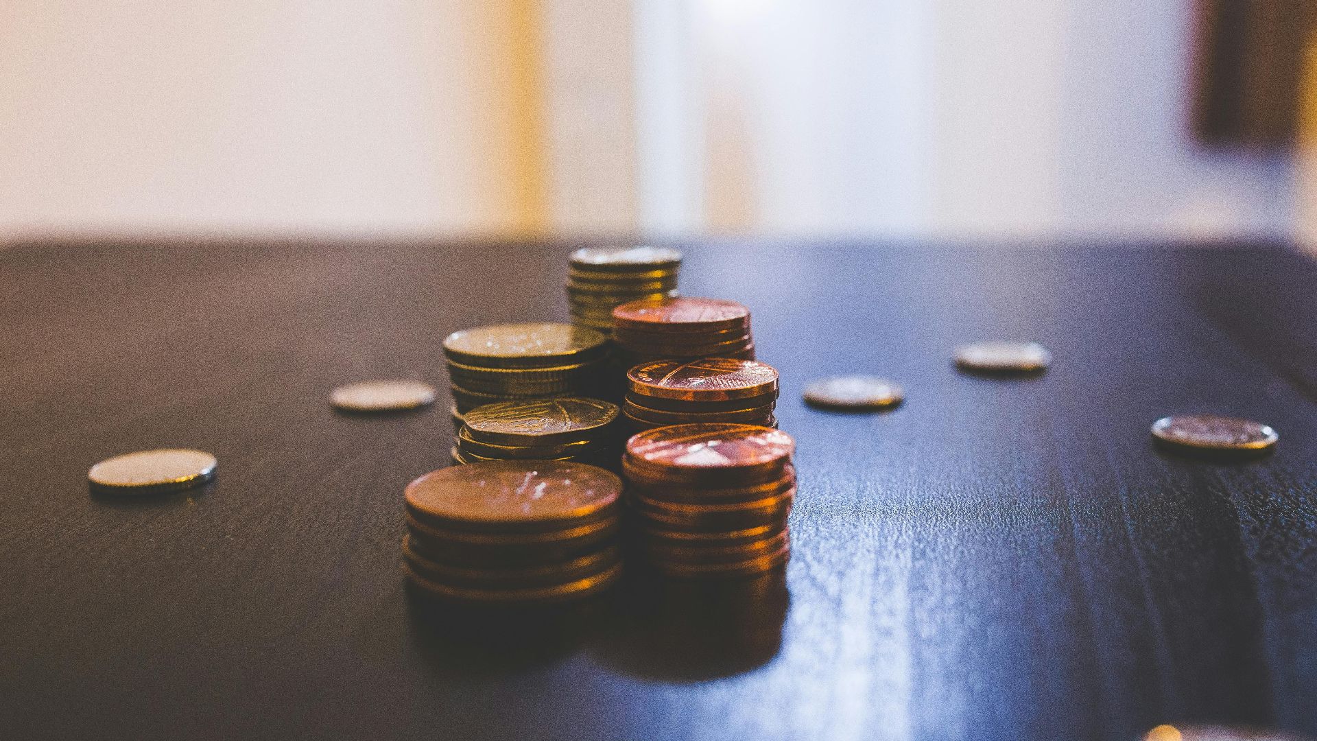 Close-up of various coins stacked on a dark table indoors.