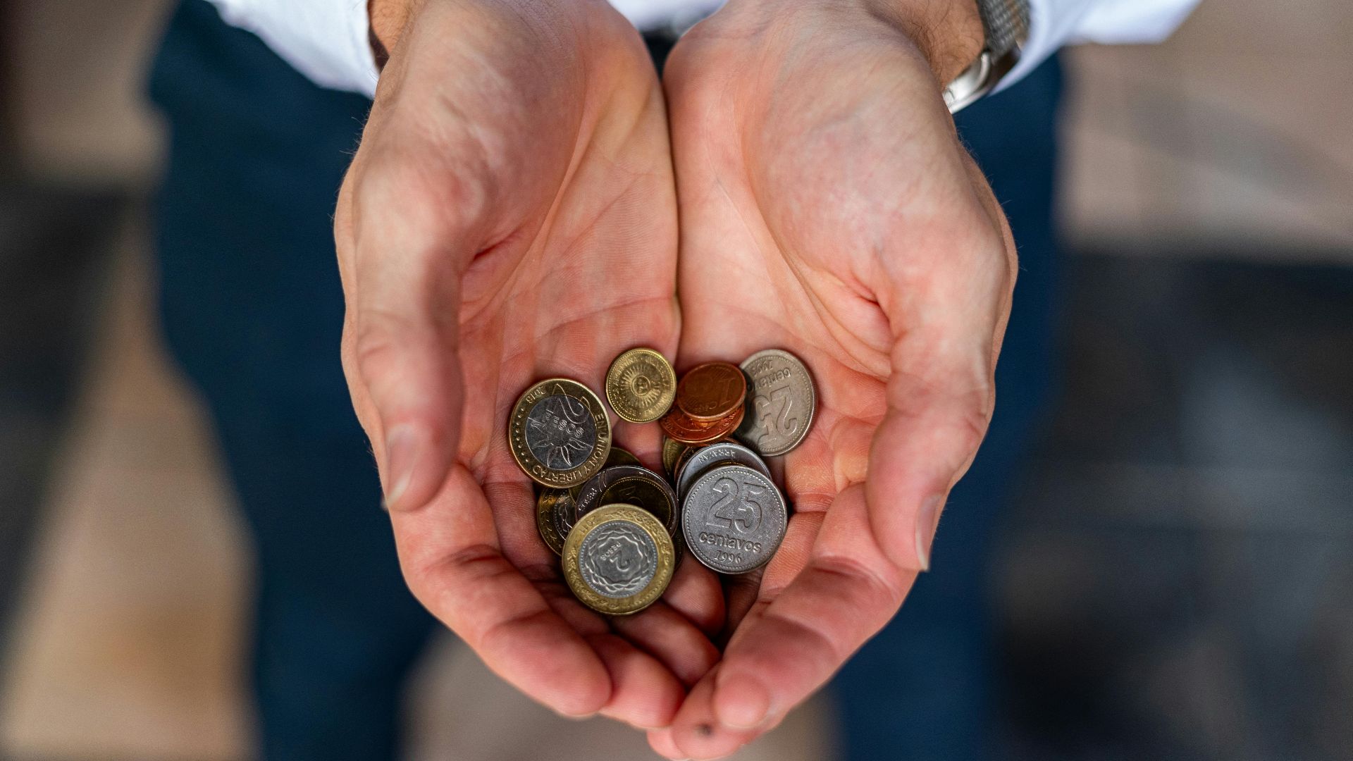 Close-up of hands holding Argentine coins, showcasing currency detail in Buenos Aires.