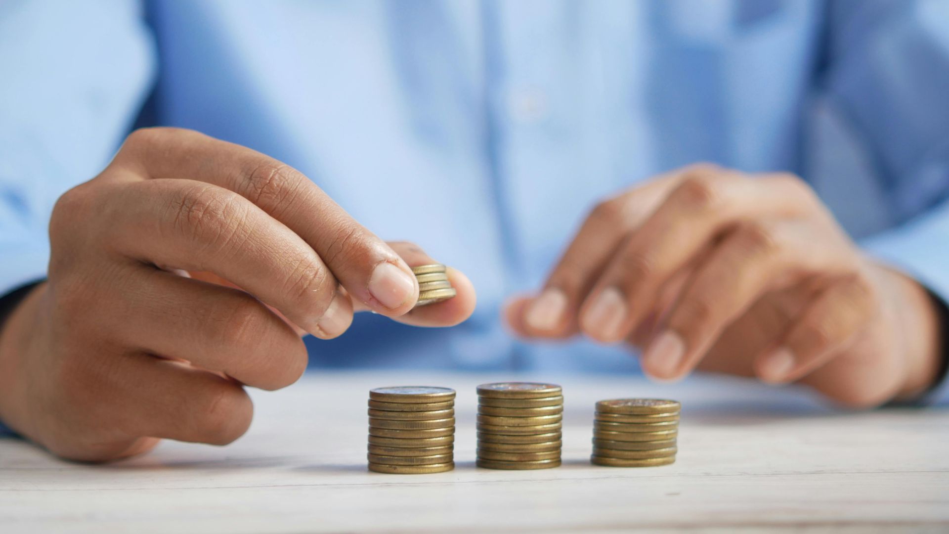 Close-up of hands stacking gold coins, symbolizing financial growth and savings.